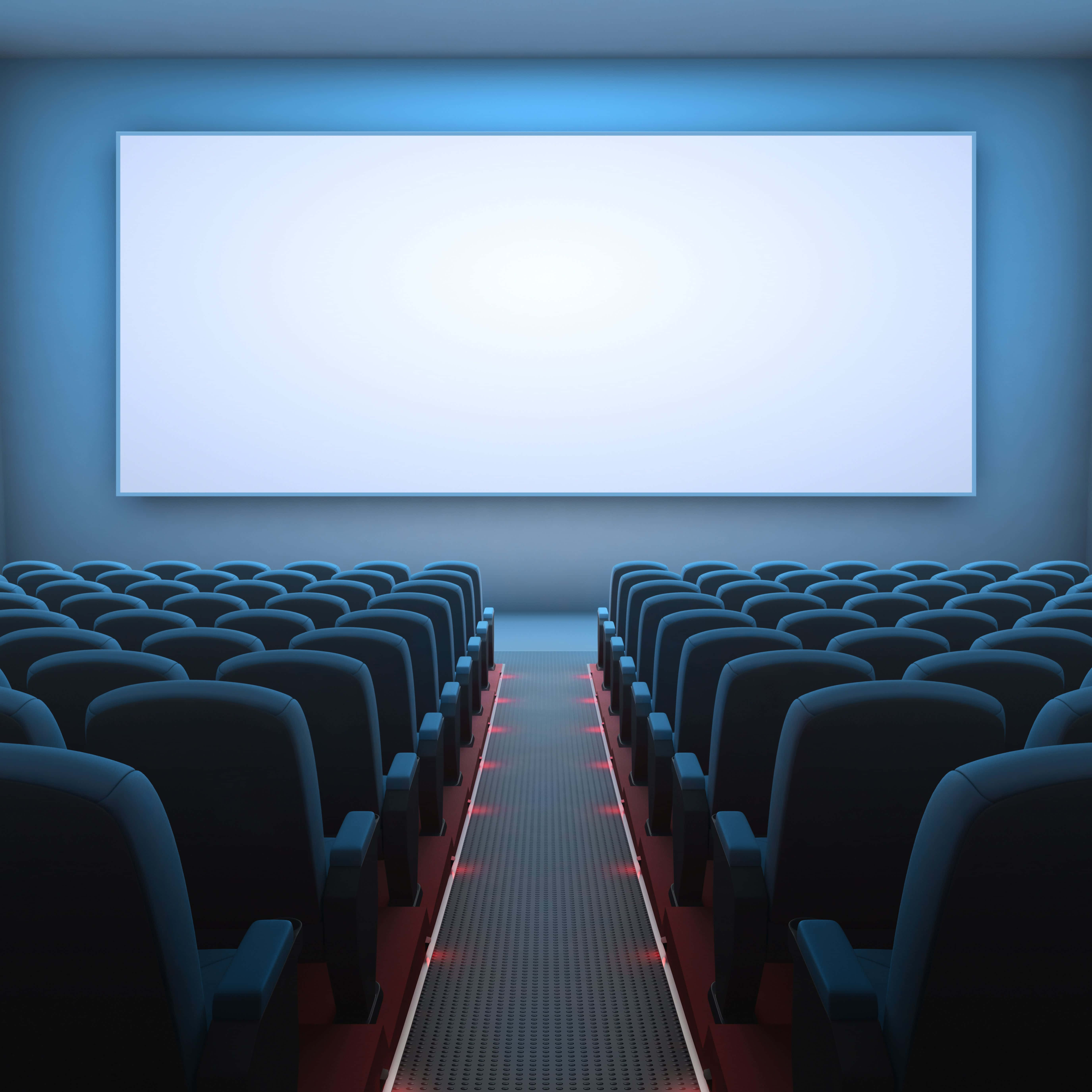 Theater 桌布 壁紙 — 一排排深色劇院座位面向昏暗電影院中發光的空白螢幕，帶有藍色環境照明。