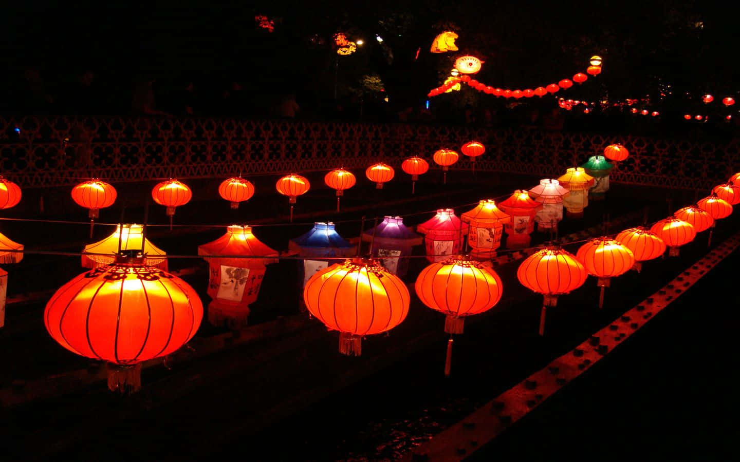 春節 桌布 壁紙 — 一排排發光的紅色燈籠在夜晚用溫暖的節日燈光照亮了一條黑暗的小路。