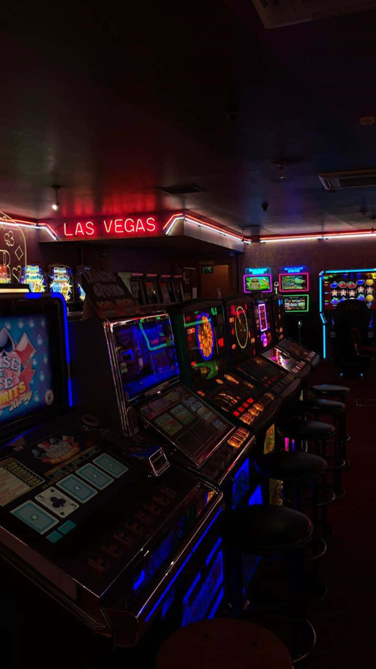 桌布 壁紙 — 一排排發光的角子機，在昏暗的賭場中，紅色霓虹燈 'LAS VEGAS' 標誌下。