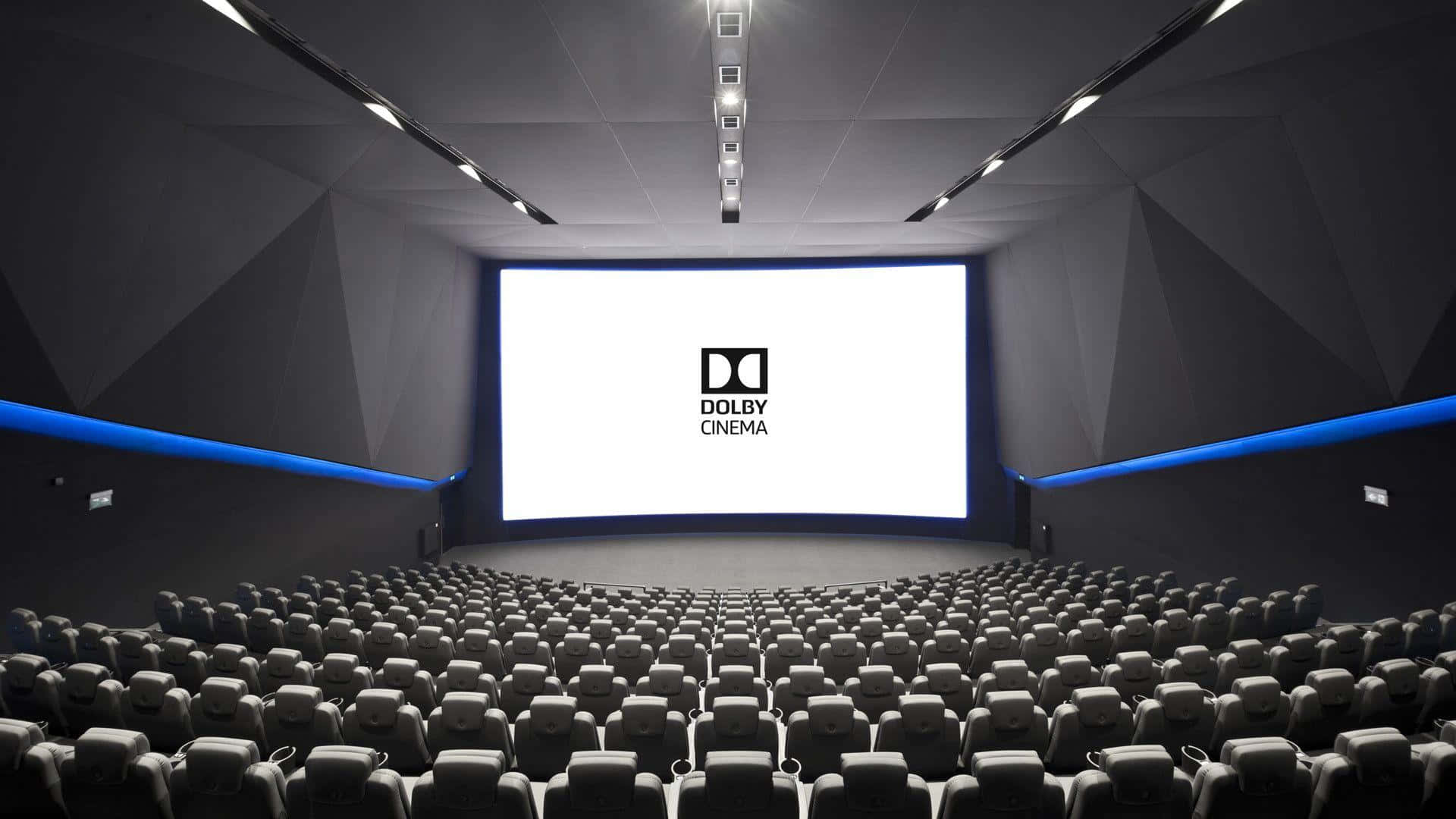 Sound 桌布 壁紙 — 一排排空黑色座椅面向發光的 Dolby Cinema 螢幕，位於時尚的黑暗影院中，帶有藍色重點照明。