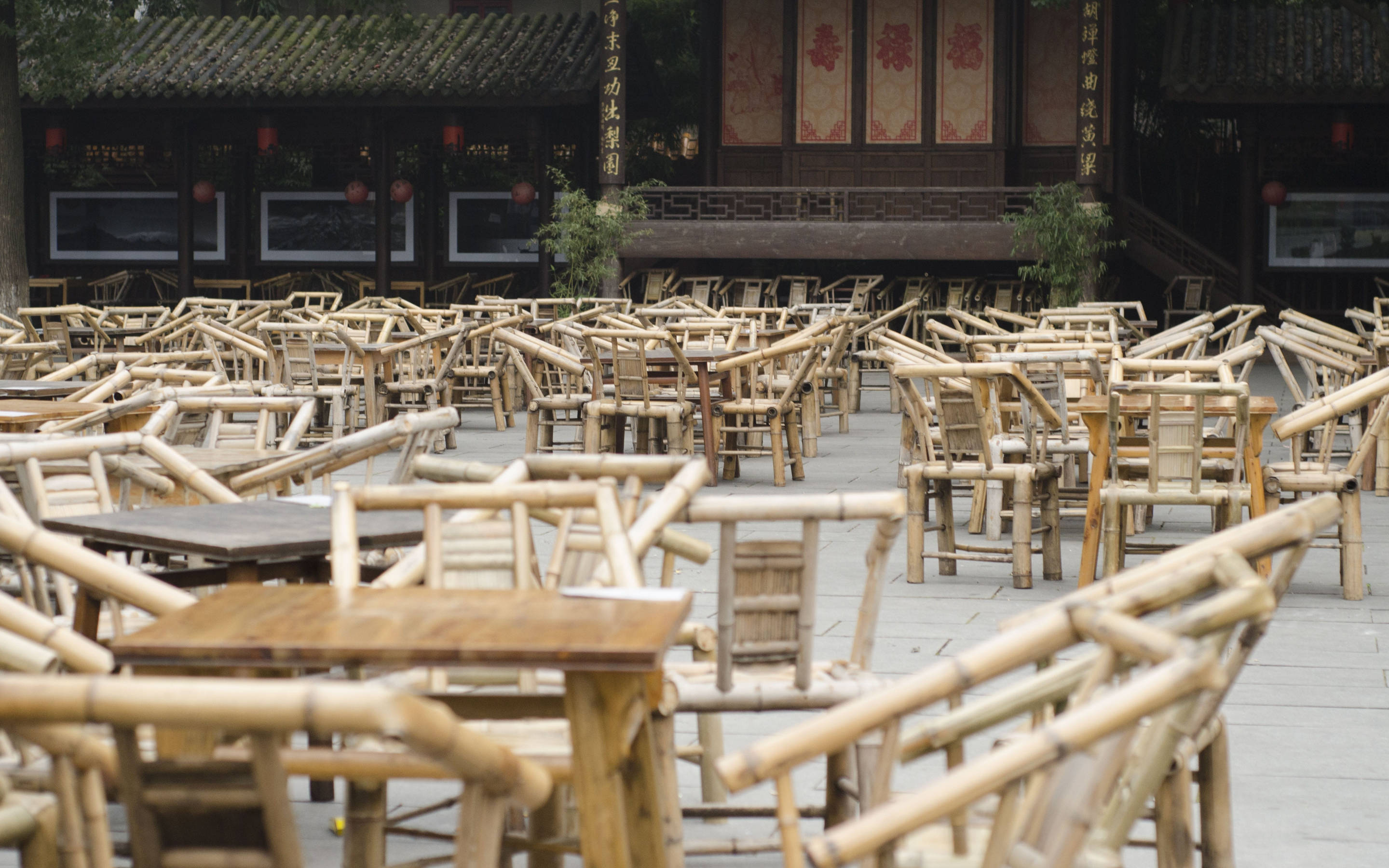 Chengdu 桌布 壁紙 — 一排排竹椅和竹桌被遺棄在傳統中式庭院中，天空陰沉。