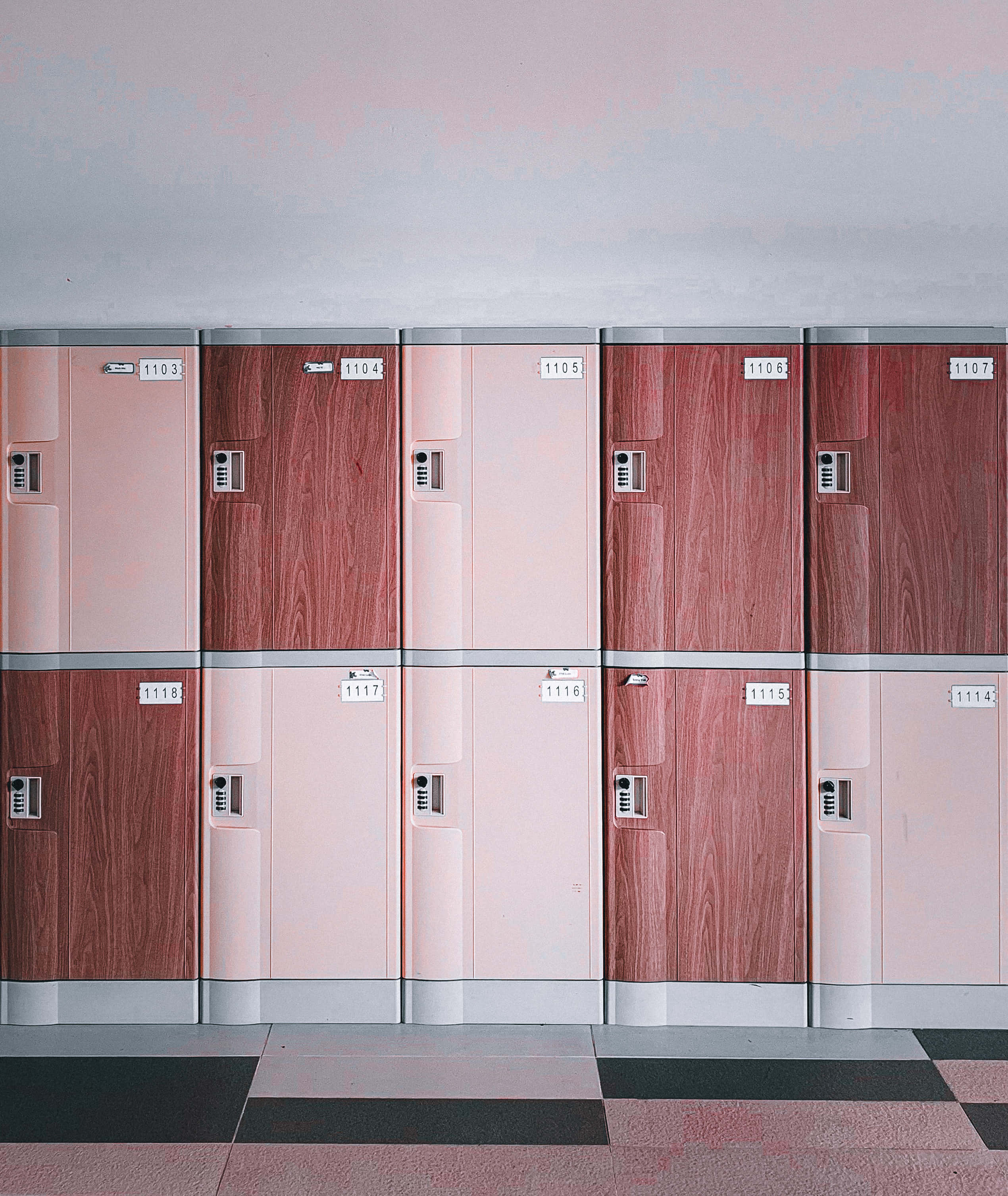 Lockers 桌布 壁紙 — 一排排粉紅色和木紋儲物櫃帶有銀色點綴，在柔和環境光下靠著淺色牆壁。