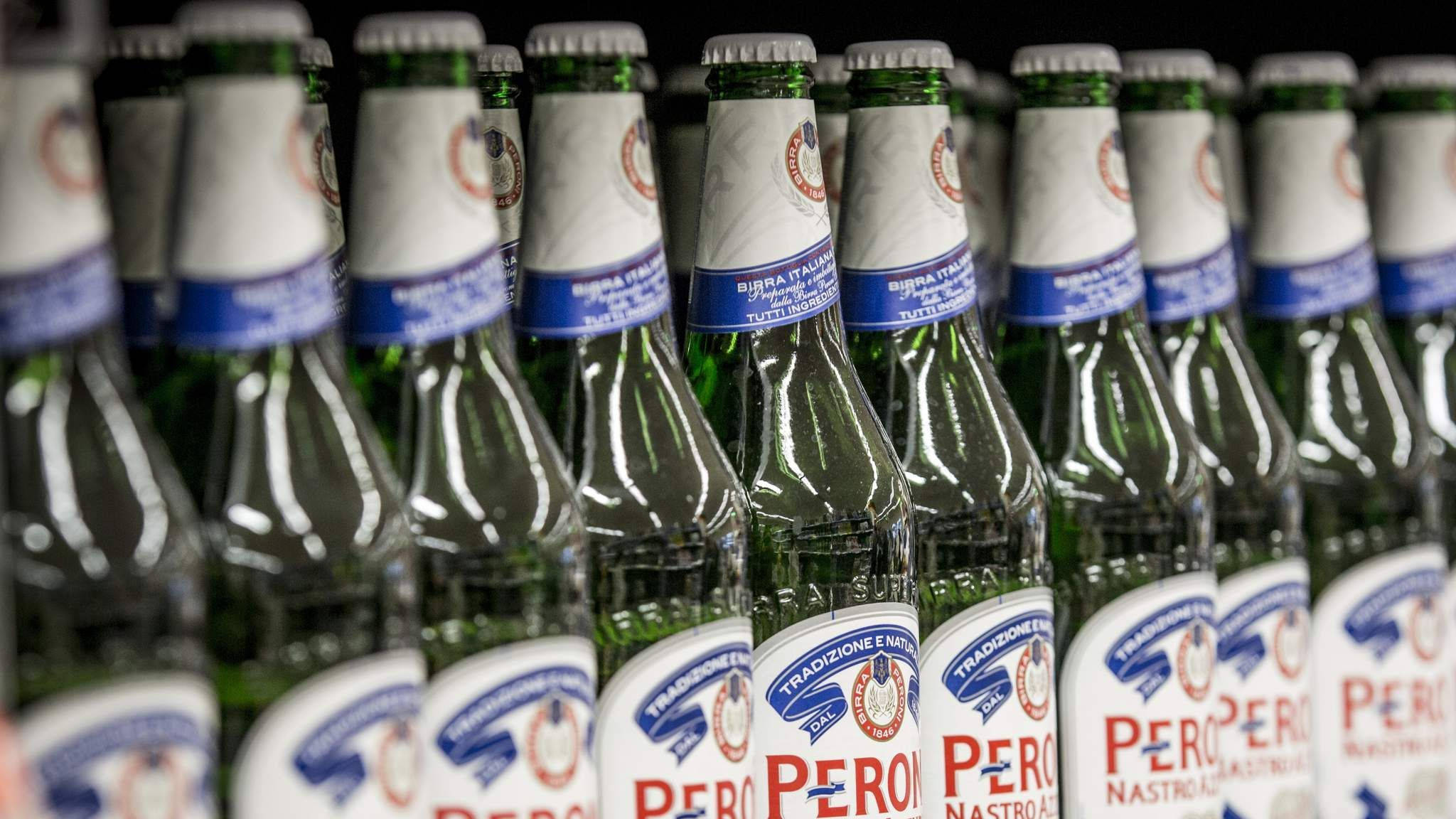 bottle 桌布 壁紙 — 一排排綠色玻璃 Peroni 啤酒瓶，帶有白色和藍色標籤，緊密排列在深色背景前。