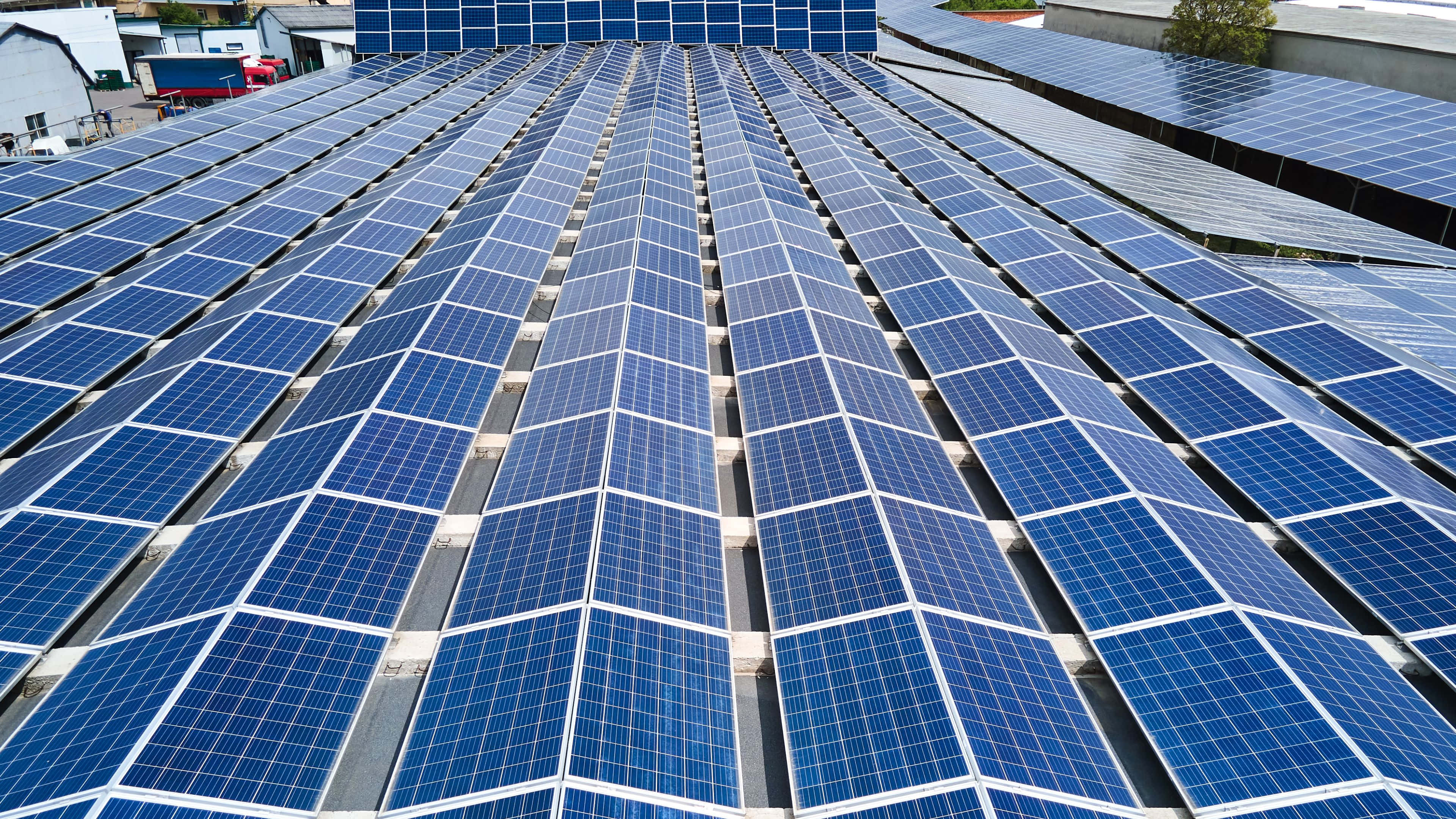 Solar Panel 桌布 壁紙 — 一排排藍色太陽能板在明亮的日光下延伸在屋頂上。