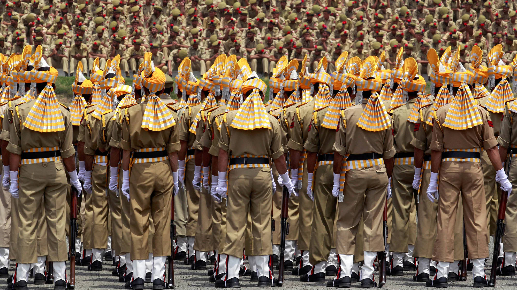 Indian 桌布 壁紙 — 一排排身穿卡其色制服和黃色頭巾的士兵以精確的軍事閱兵隊形立正。