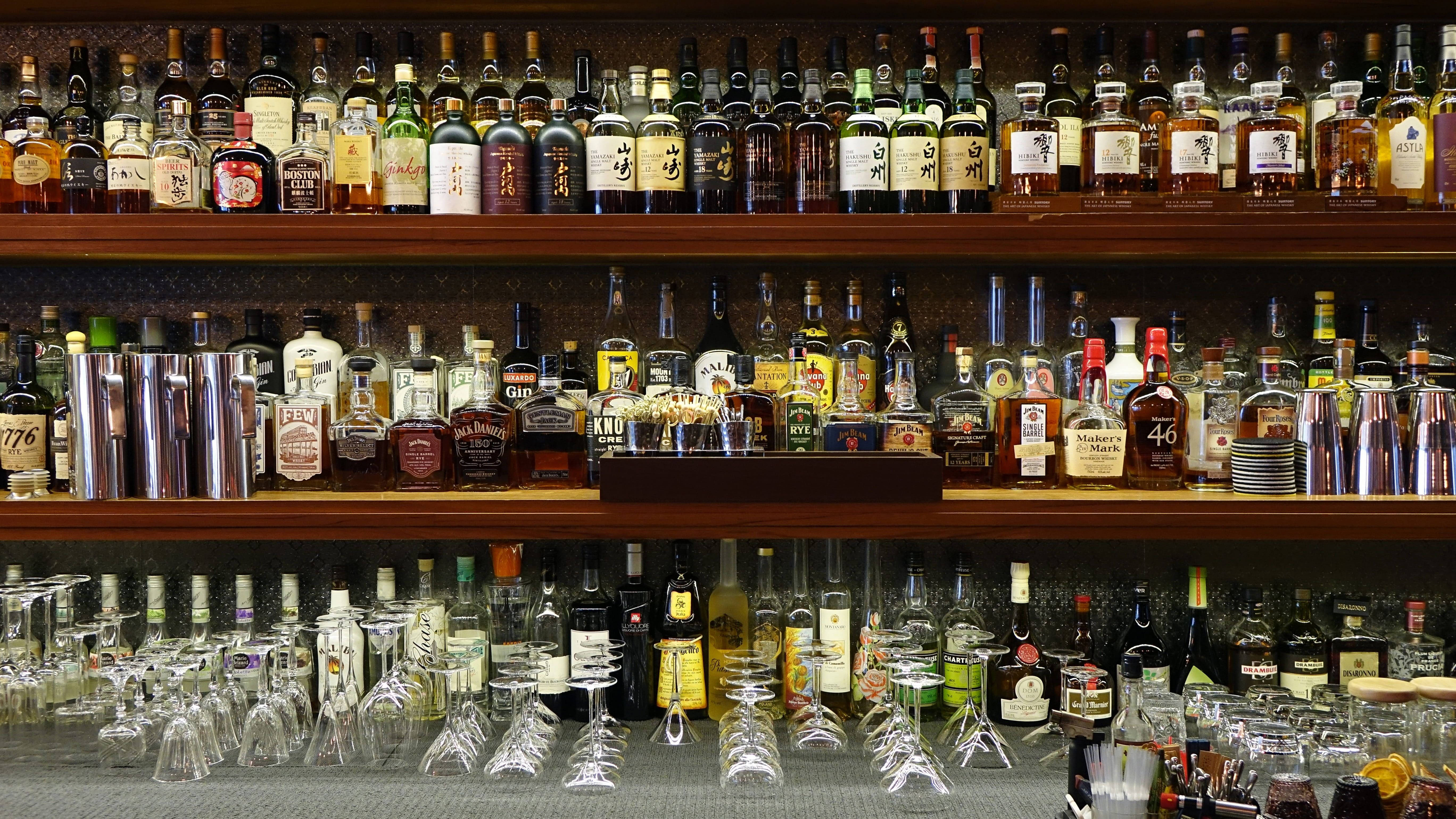 Bar 桌布 壁紙 — 一排排酒瓶和雞尾酒杯整齊地排列在吧檯後方的木架上。