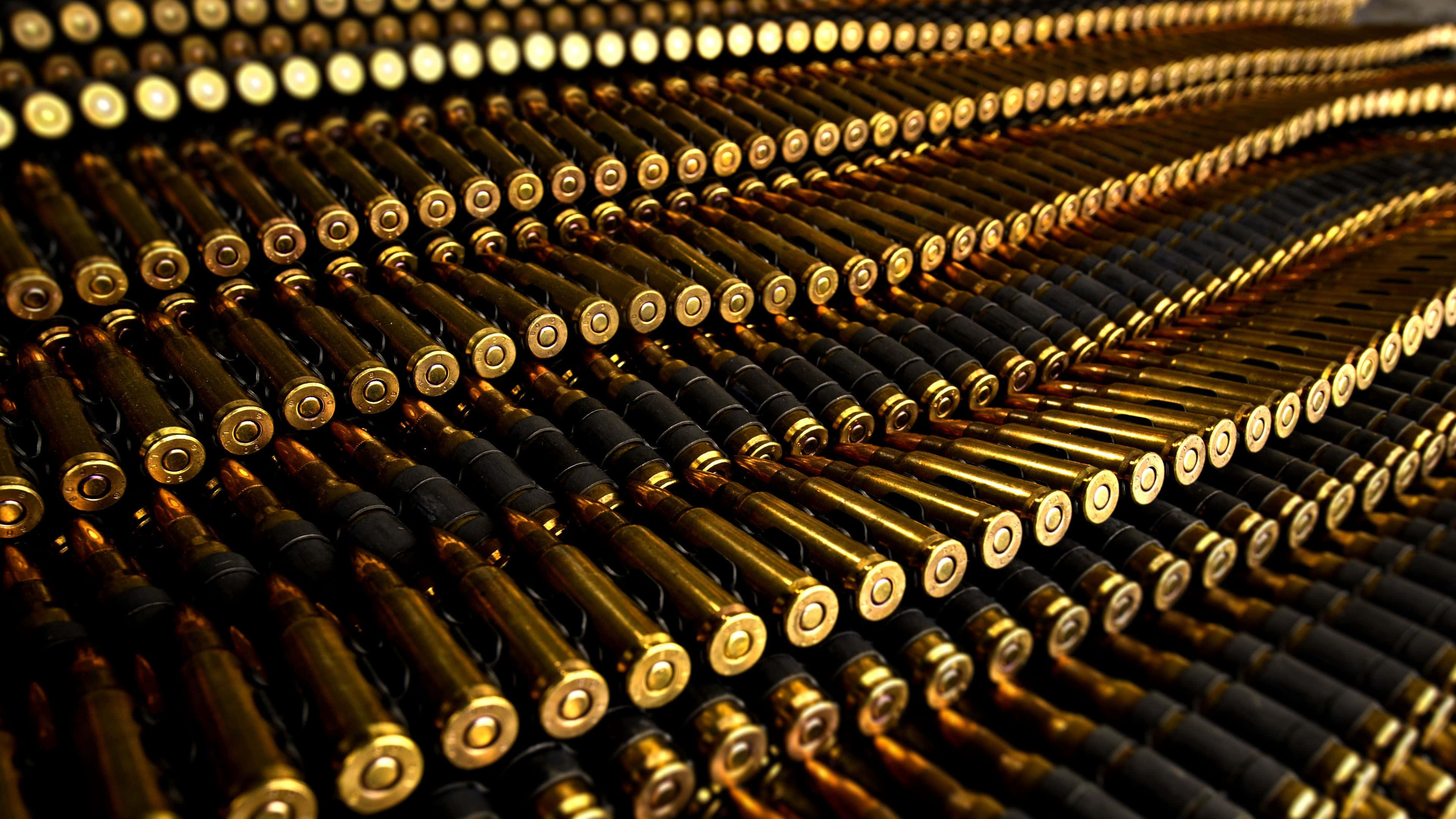 bullet 桌布 壁紙 — 一排排黃銅和黑色步槍彈藥在溫暖燈光下以對角線圖案排列。
