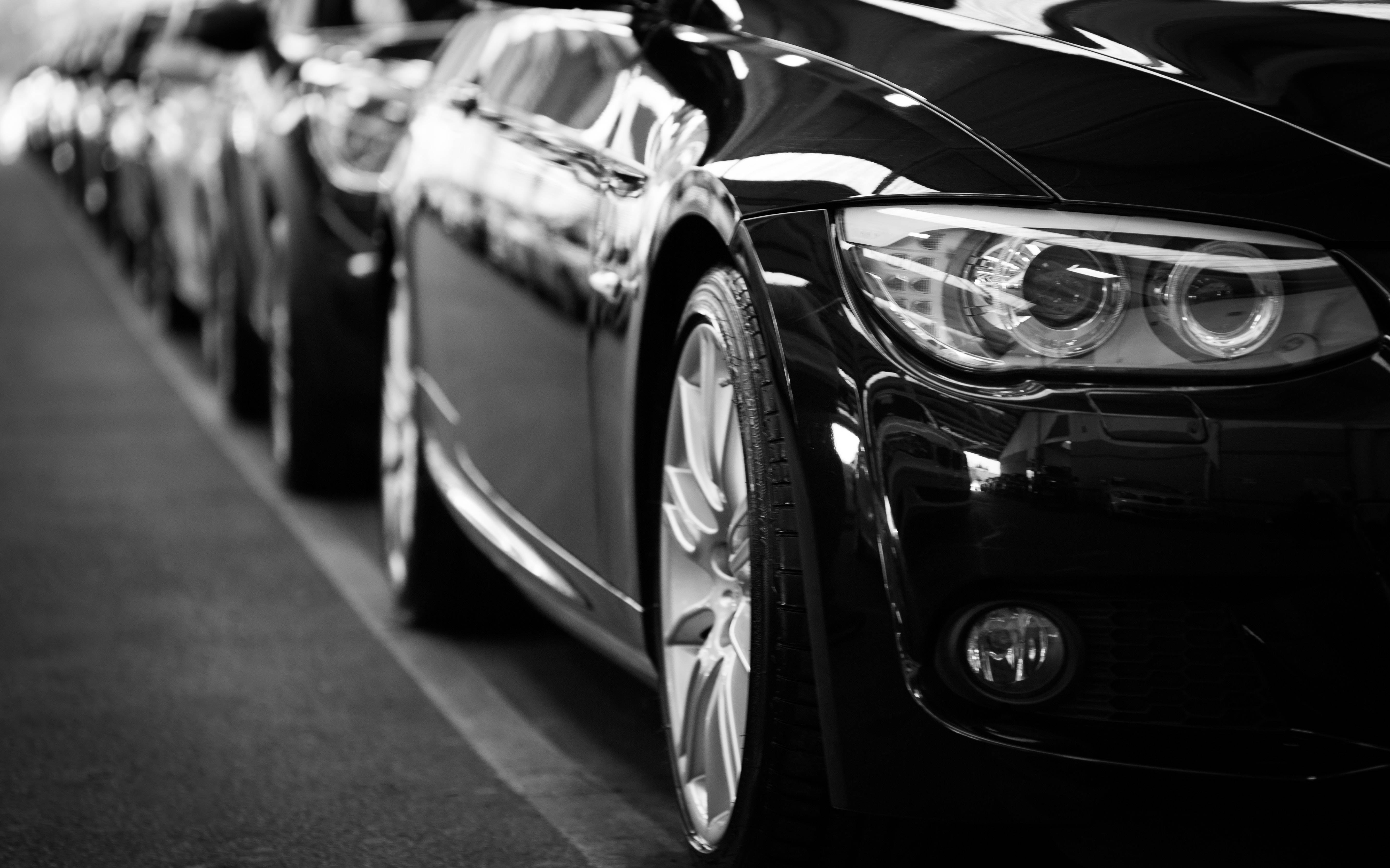 parking 桌布 壁紙 — 一排時尚的黑色豪華汽車排列在單色展示中，展現光澤飾面和銳利的現代設計。