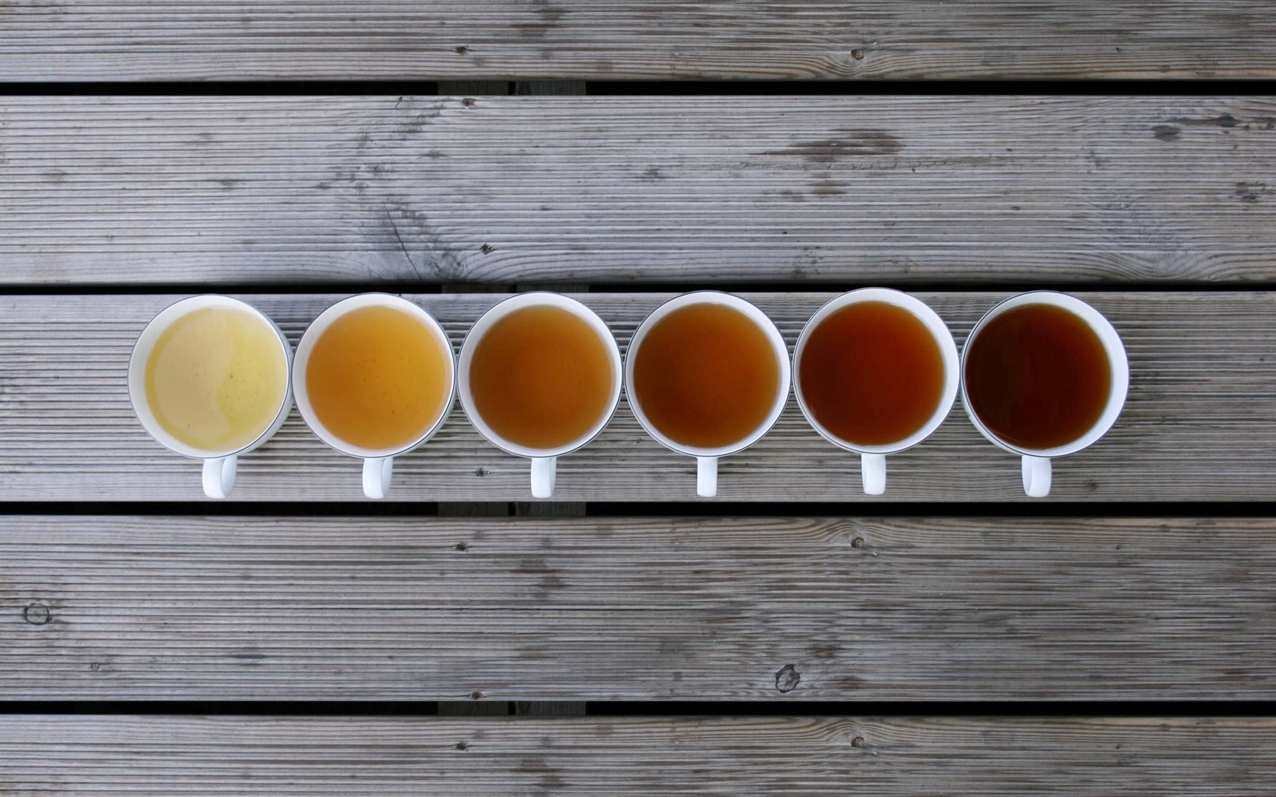 一排杯子裡裝著不同的茶 壁紙