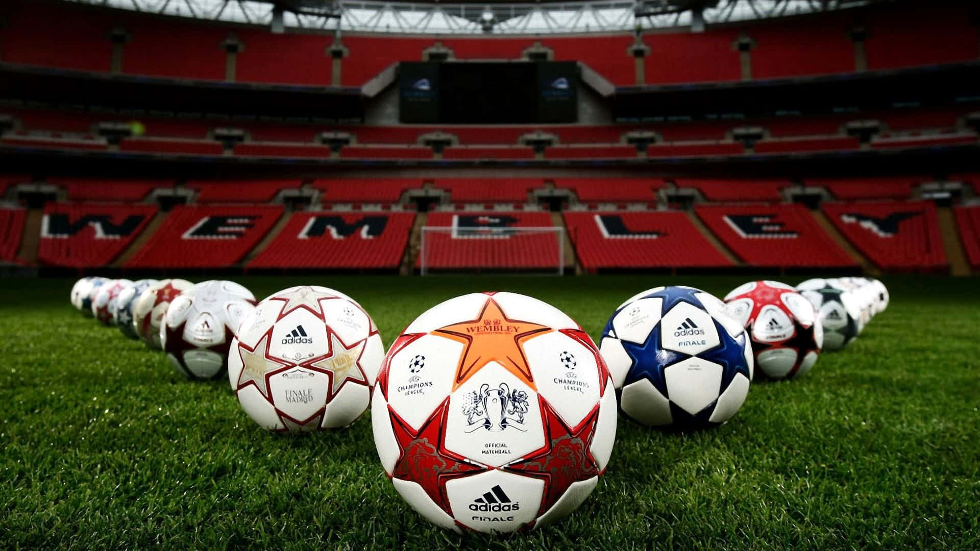 Soccer 4K 桌布 壁紙 — 一排歐冠足球放在溫布利球場標誌性紅色座椅前的鮮綠色草地上。