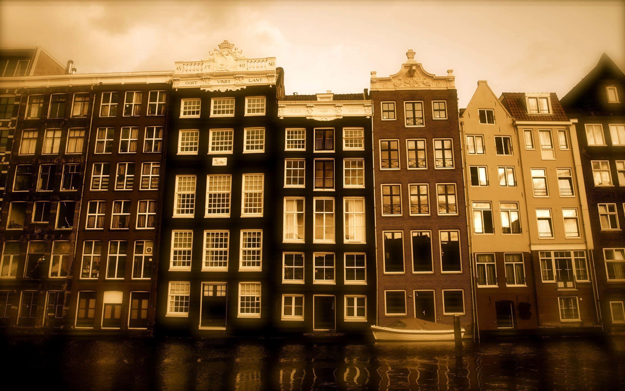 Sepia 桌布 壁紙 — 一排歷史悠久的阿姆斯特丹運河房屋沐浴在溫暖的懷舊色調光線中，一艘小船停靠在岸邊。