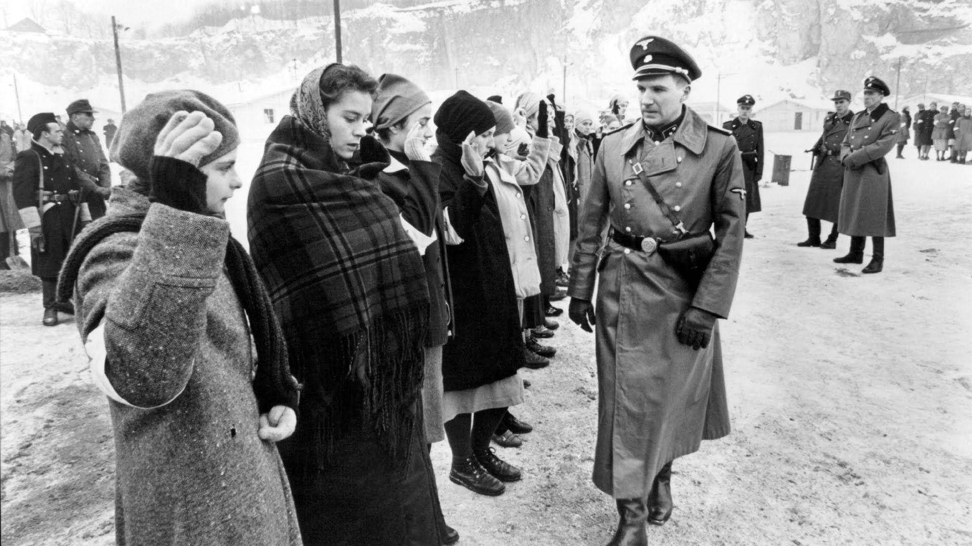 電影動圖 桌布 壁紙 — 一排穿著冬季外套和頭巾的女性在雪地營地中向一名制服軍官敬禮。
