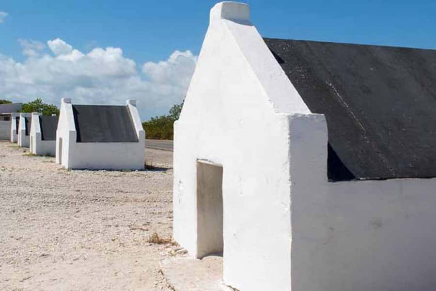 Hut 桌布 壁紙 — 一排純白簡約的混凝土建築，黑色屋頂，矗立在藍天白雲下。