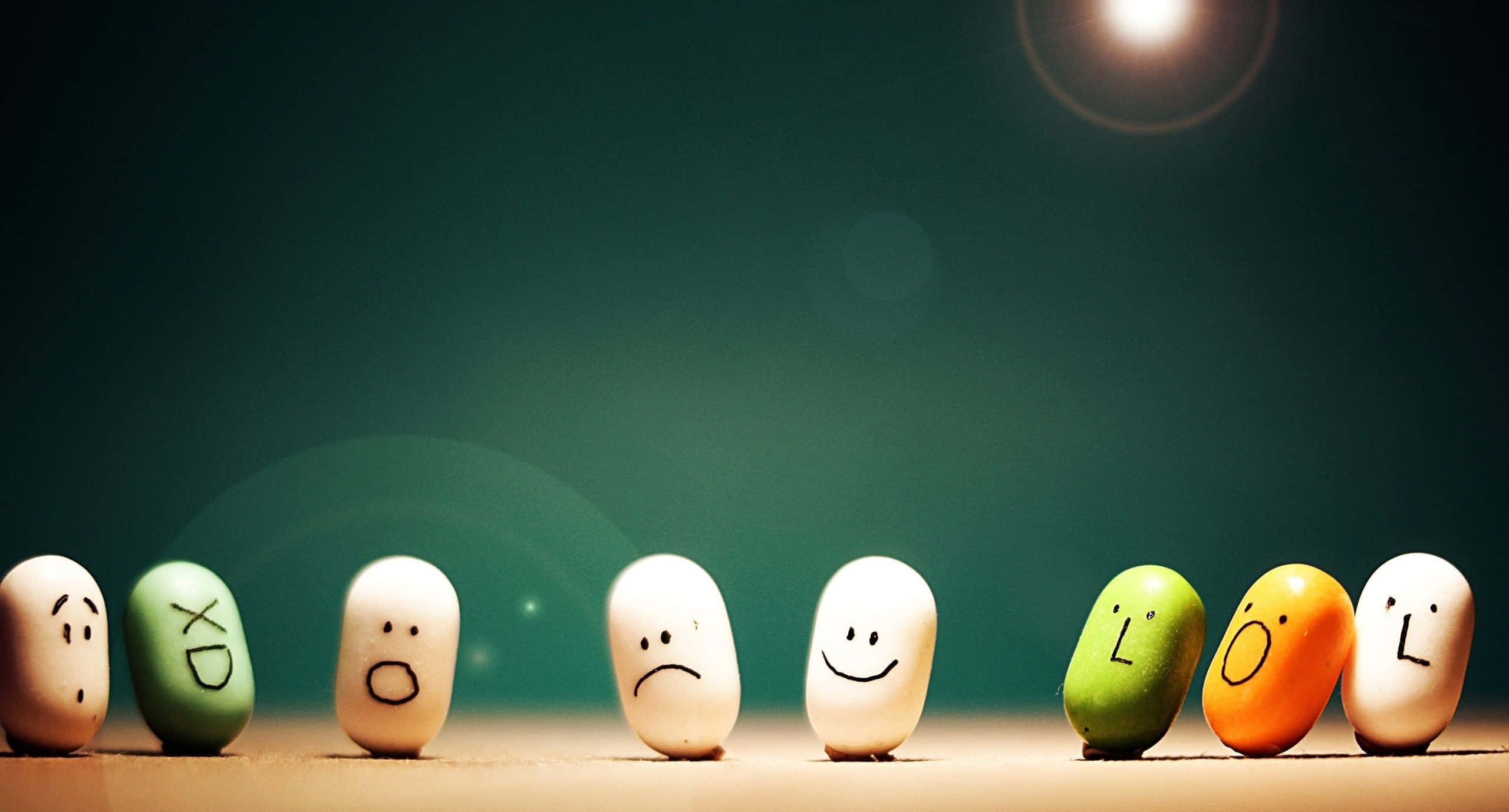 Happy Mood 桌布 壁紙 — 一排色彩繽紛的石頭，上面畫有表情的臉孔，在溫暖的聚光燈下，以深綠色背景襯托。