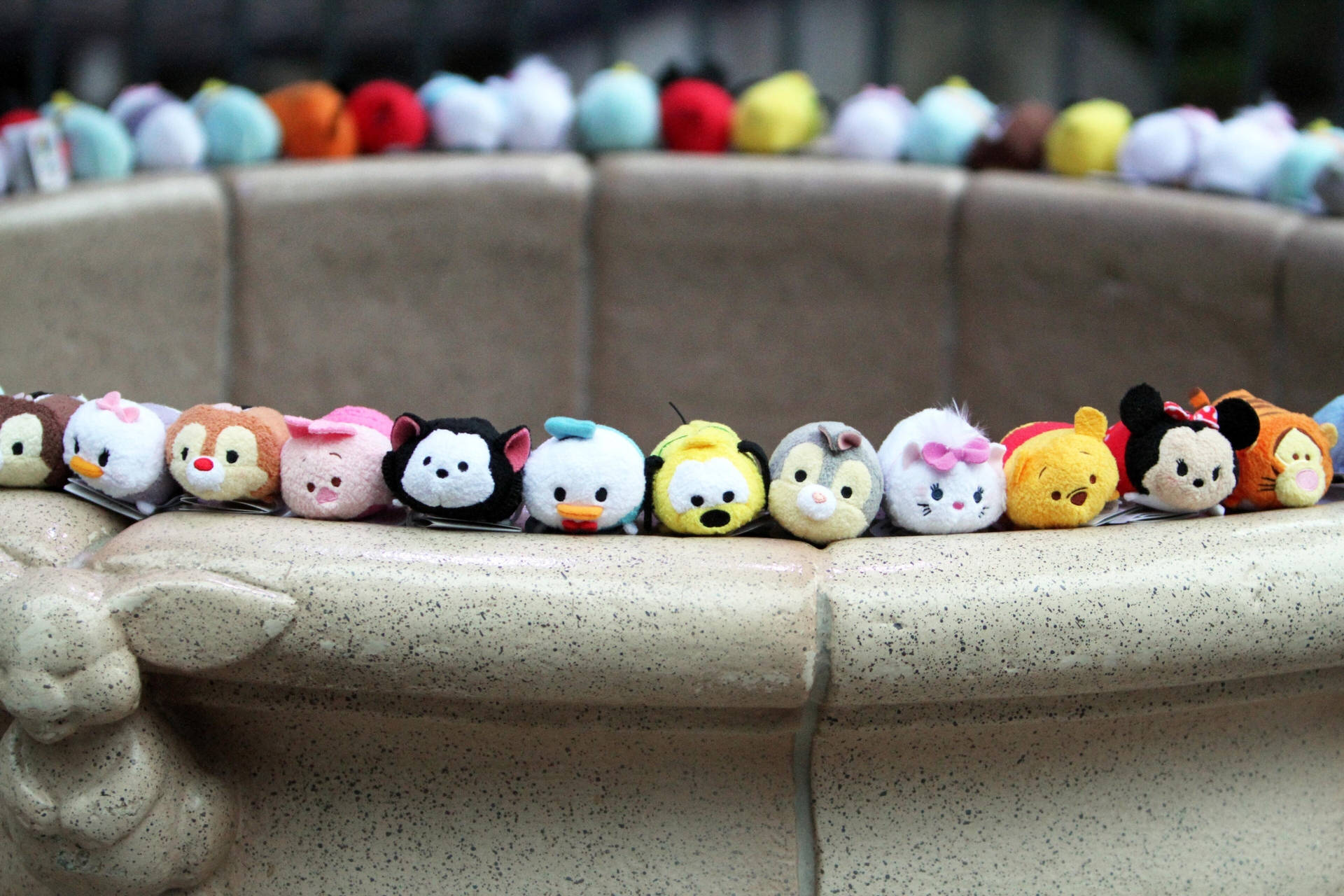 一排迪士尼 Tsum Tsum 毛絨玩具在石噴泉邊緣上。 — Tsum tsum 壁紙
