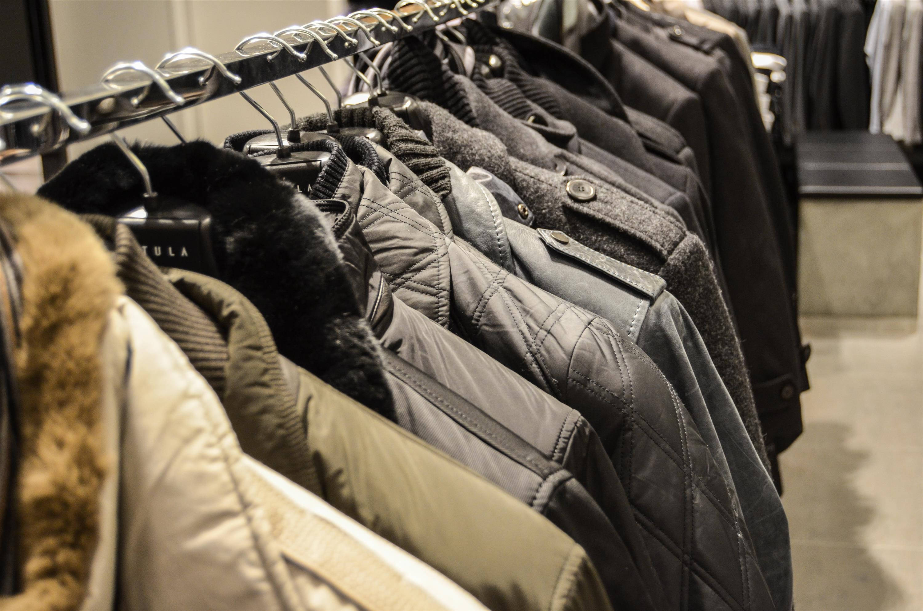 Clothes 桌布 壁紙 — 一排色調柔和的冬季外套整齊地掛在現代零售店的金屬架上。