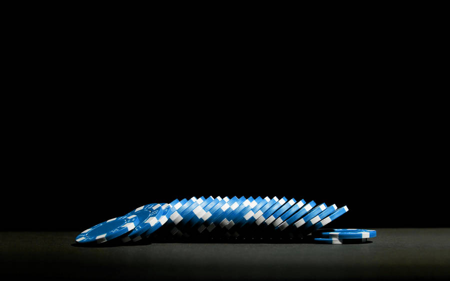 Poker 桌布 壁紙 — 一排藍色和白色的籌碼以連鎖骨牌效應排列在純黑色背景上。