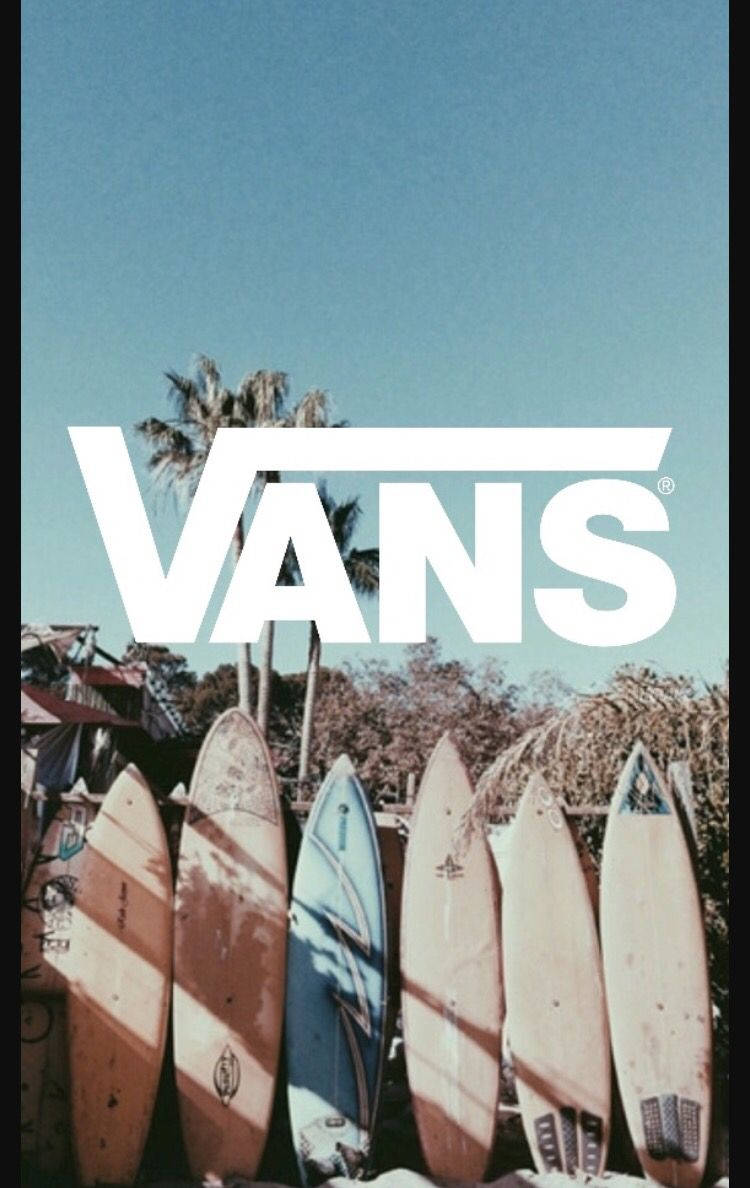 Vans 桌布 壁紙 — 一排風化的衝浪板靠在圍欄上，在晴朗的藍天下，有棕櫚樹和一個大型VANS標誌覆蓋層。