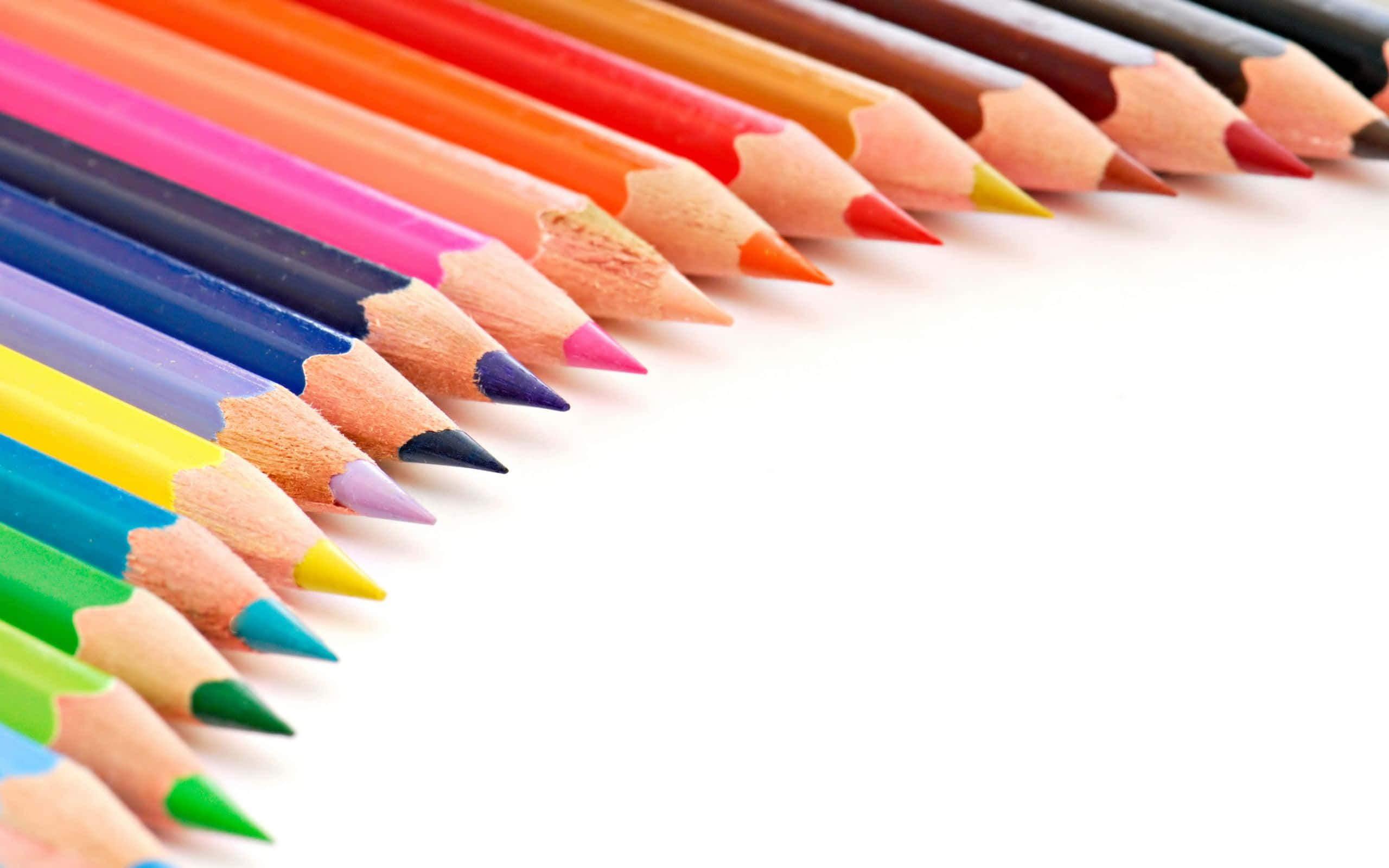 pencil 桌布 壁紙 — 一排鮮豔的斜向排列的削尖彩色鉛筆，木質筆身，明亮的筆尖，在潔白的背景上。