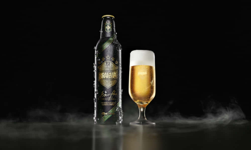 alcohol 桌布 壁紙 — 一支冰涼的Brahma啤酒瓶和一杯裝有金色液體和白色泡沫的玻璃杯放在黑暗的表面上，周圍有薄霧繚繞。