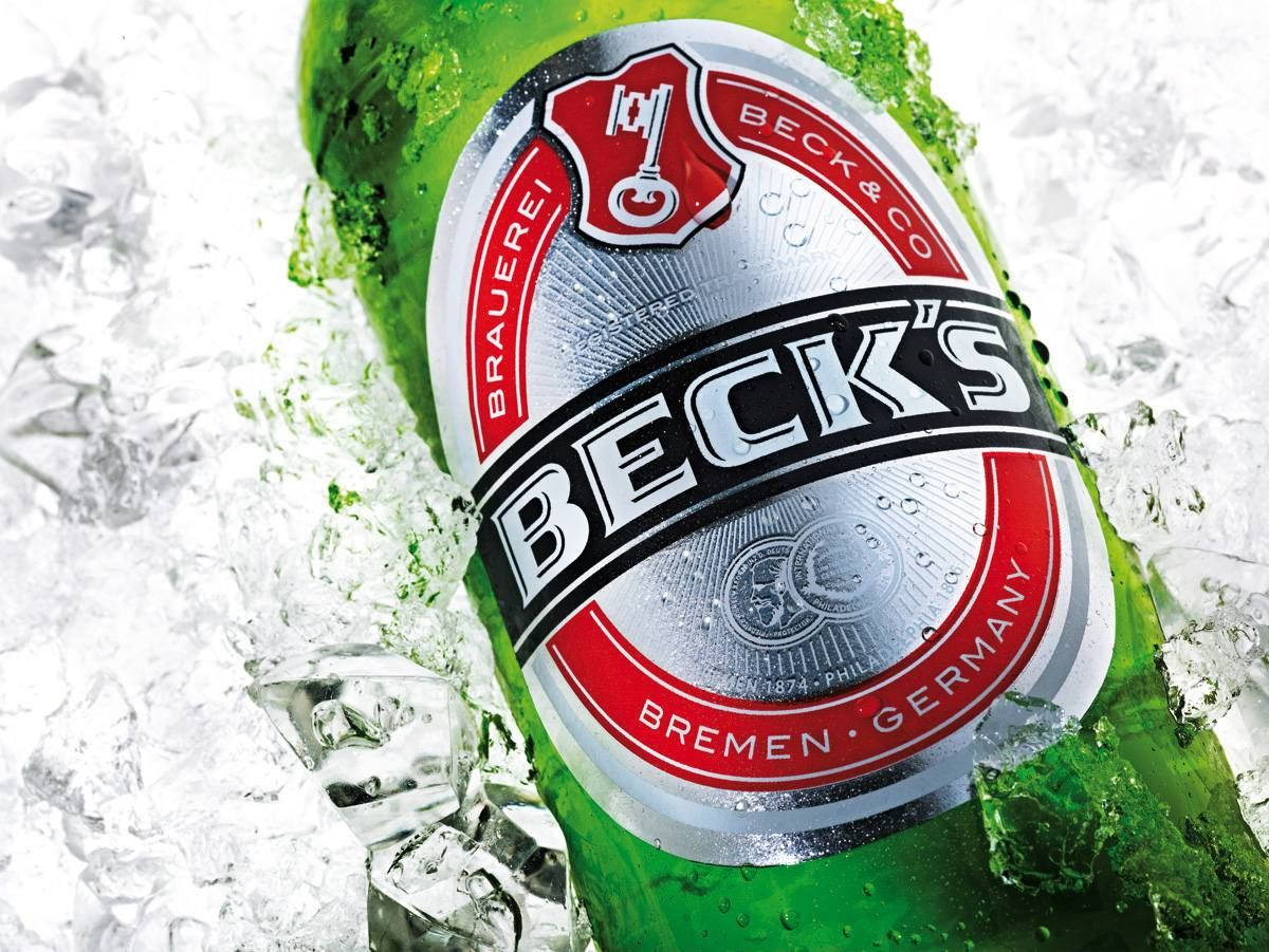 Beer 桌布 壁紙 — 一支冰涼的綠色Beck's啤酒瓶，嵌在閃閃發光的冰塊中，表面凝結的水珠滴落。