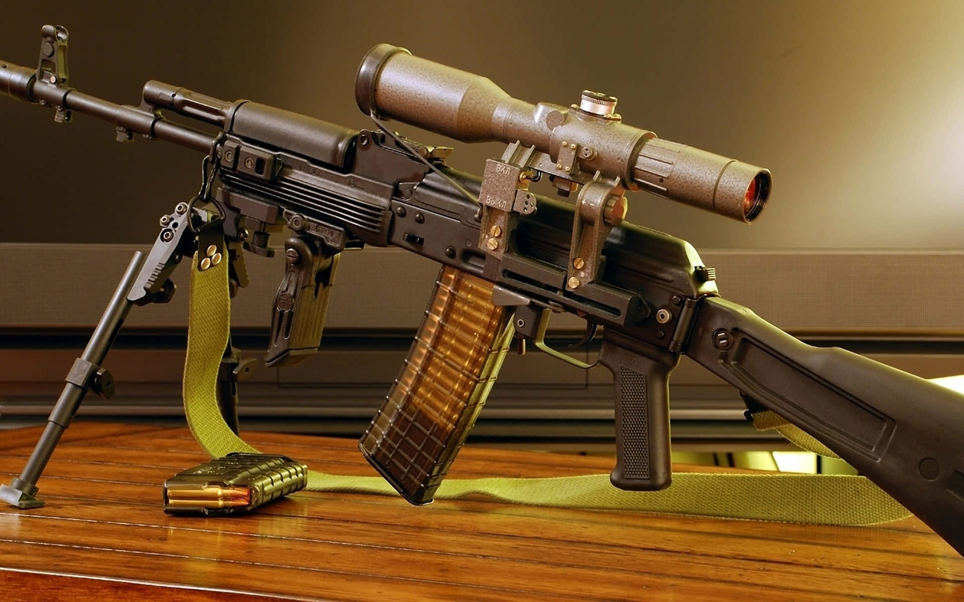 Pubg Guns 桌布 壁紙 — 一支帶瞄準鏡和彈匣的軍用突擊步槍，放在木桌上，附有綠色背帶和額外彈藥。