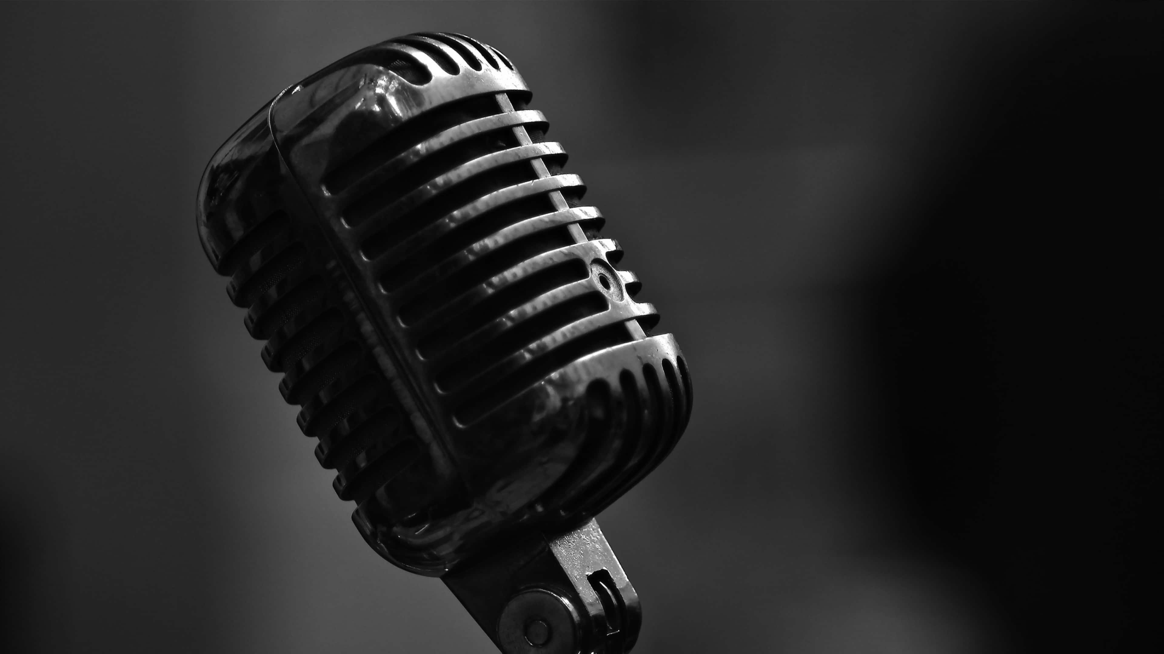 Sound 桌布 壁紙 — 一支復古條紋麥克風在柔和模糊的深色背景下以單色閃耀。