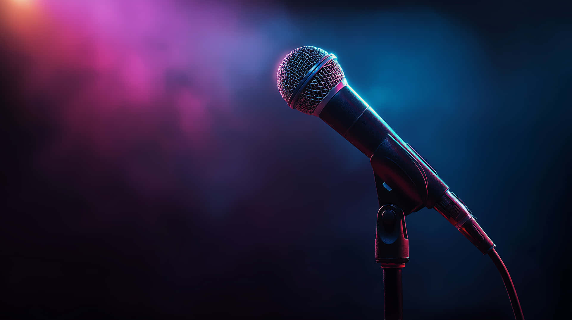 Close-Up Stage Microphone with Dynamic Colorful Light Reflections 壁紙 — 一支復古麥克風在支架上，在煙霧瀰漫的黑暗背景下，在充滿活力的粉紅色和藍色舞台燈光下閃耀。
