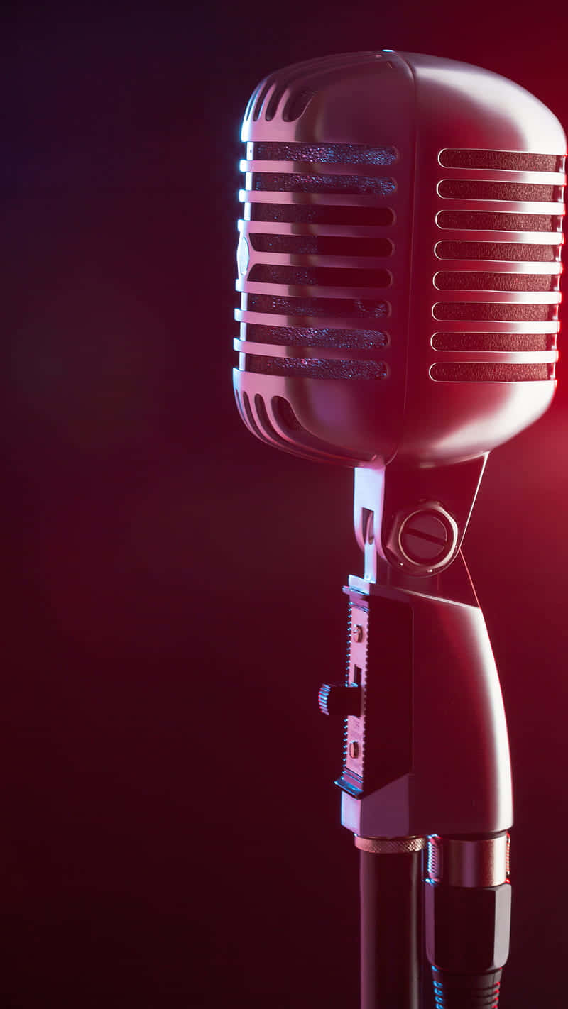 mic drop 桌布 壁紙 — 一支復古麥克風在黑暗背景下發出紅光，營造出戲劇性的舞台氛圍。