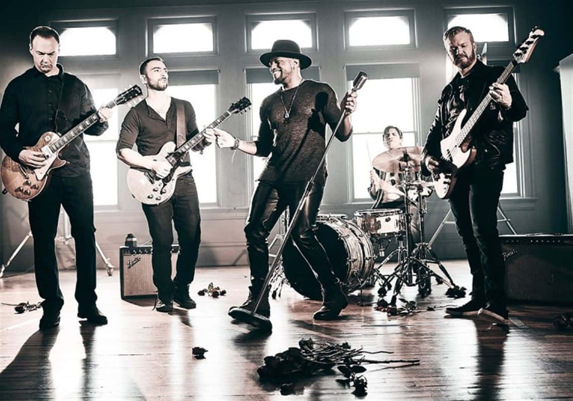 band 桌布 壁紙 — 一支搖滾樂隊在陽光充足的房間裡充滿活力地表演，有吉他、鼓和散落在地板上的玫瑰。