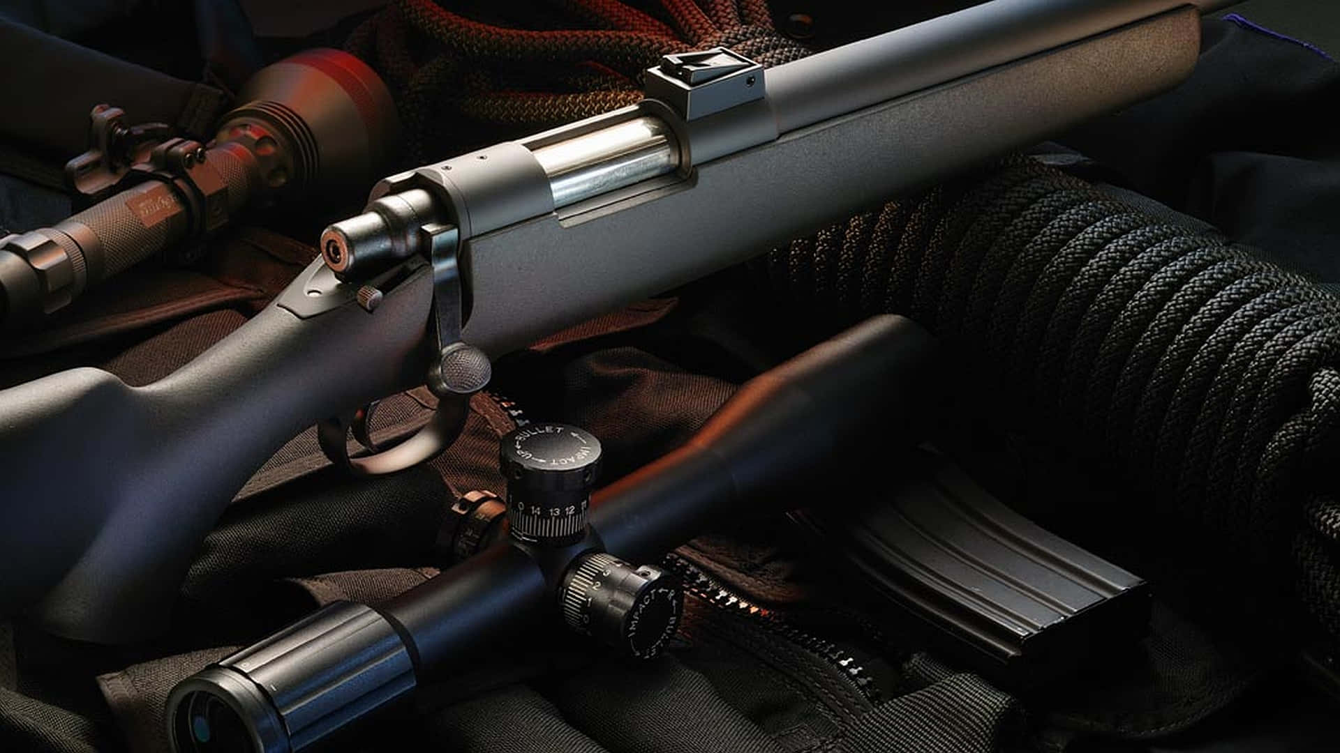 Rifle 桌布 壁紙 — 一支時尚的戰術步槍配備瞄準鏡和彈匣，在戲劇性的燈光下放置在堅固的裝備上。