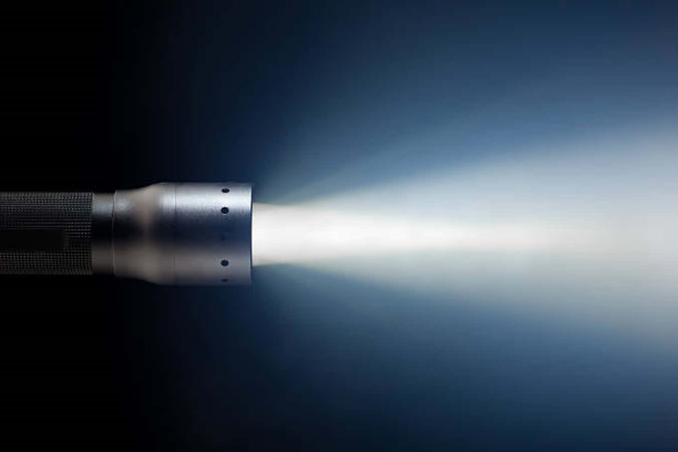 Flashlight 桌布 壁紙 — 一支時尚的手電筒在深藍色漸變背景上發出明亮的白色光束。