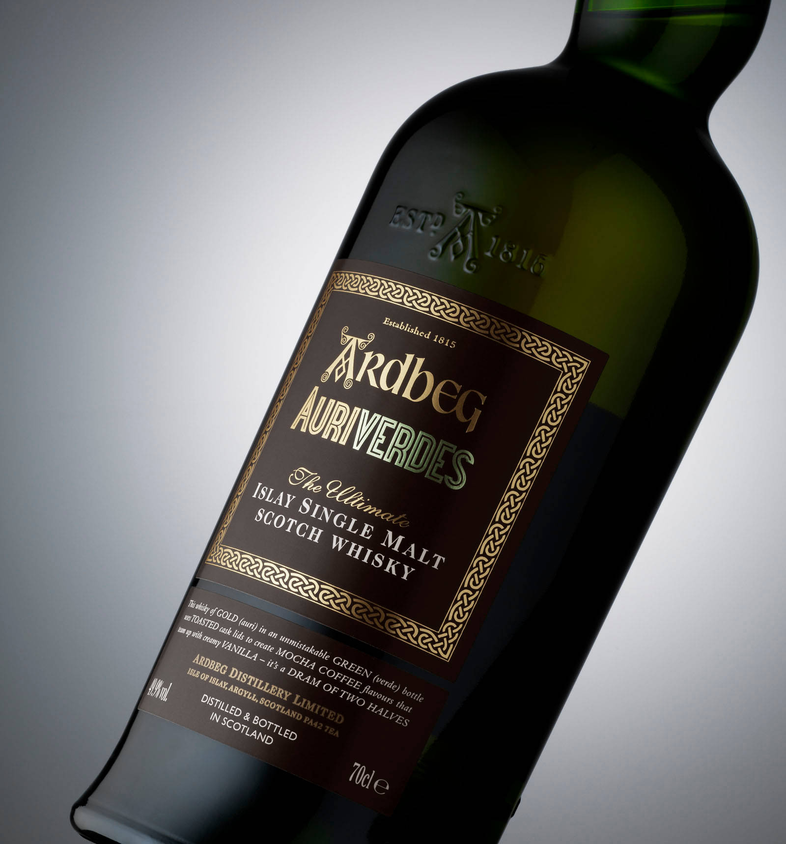 bottle 桌布 壁紙 — 一支時尚的綠色Ardbeg Auriverdes威士忌酒瓶，傾斜放置在柔和的灰色漸變背景前。