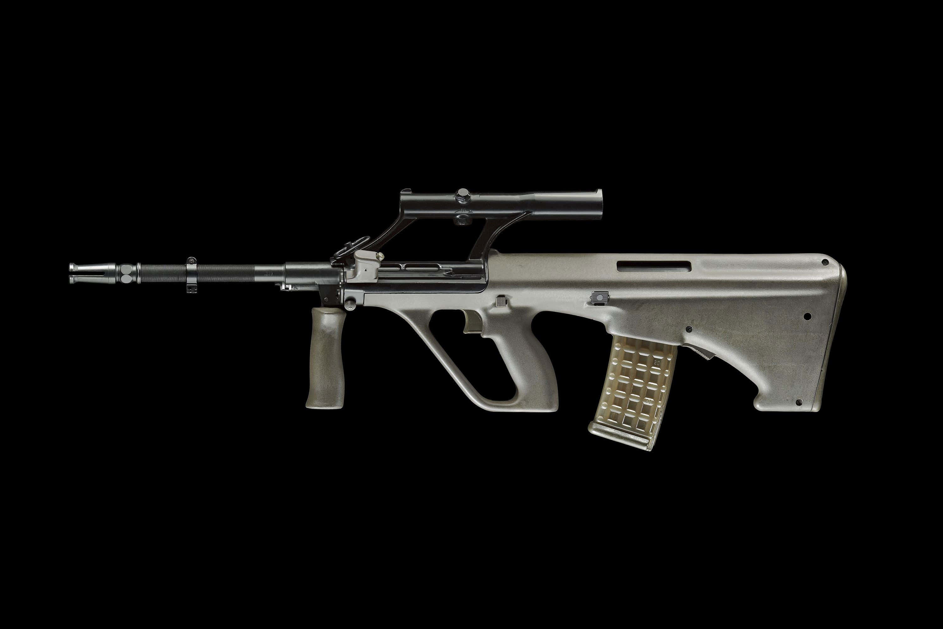 Rifle 桌布 壁紙 — 一支時尚的銀色突擊步槍配金色彈匣，水平放置在純黑色背景上。