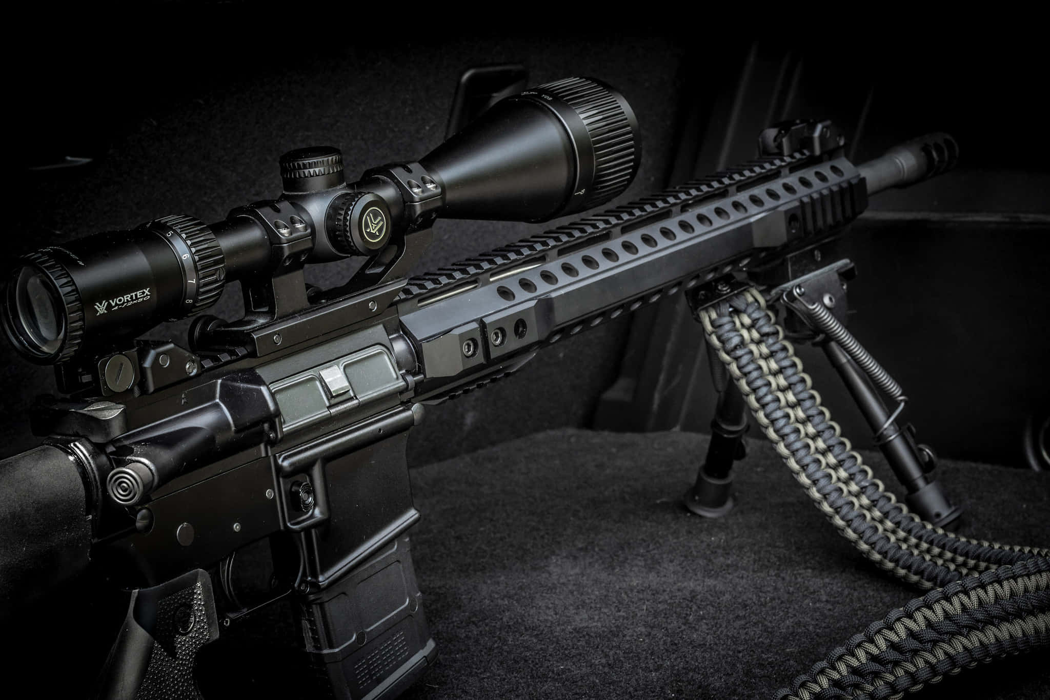 Rifle 桌布 壁紙 — 一支時尚的黑色戰術步槍，配備Vortex瞄準鏡和兩腳架，在戲劇性的工作室燈光下放置在深色紋理表面上。