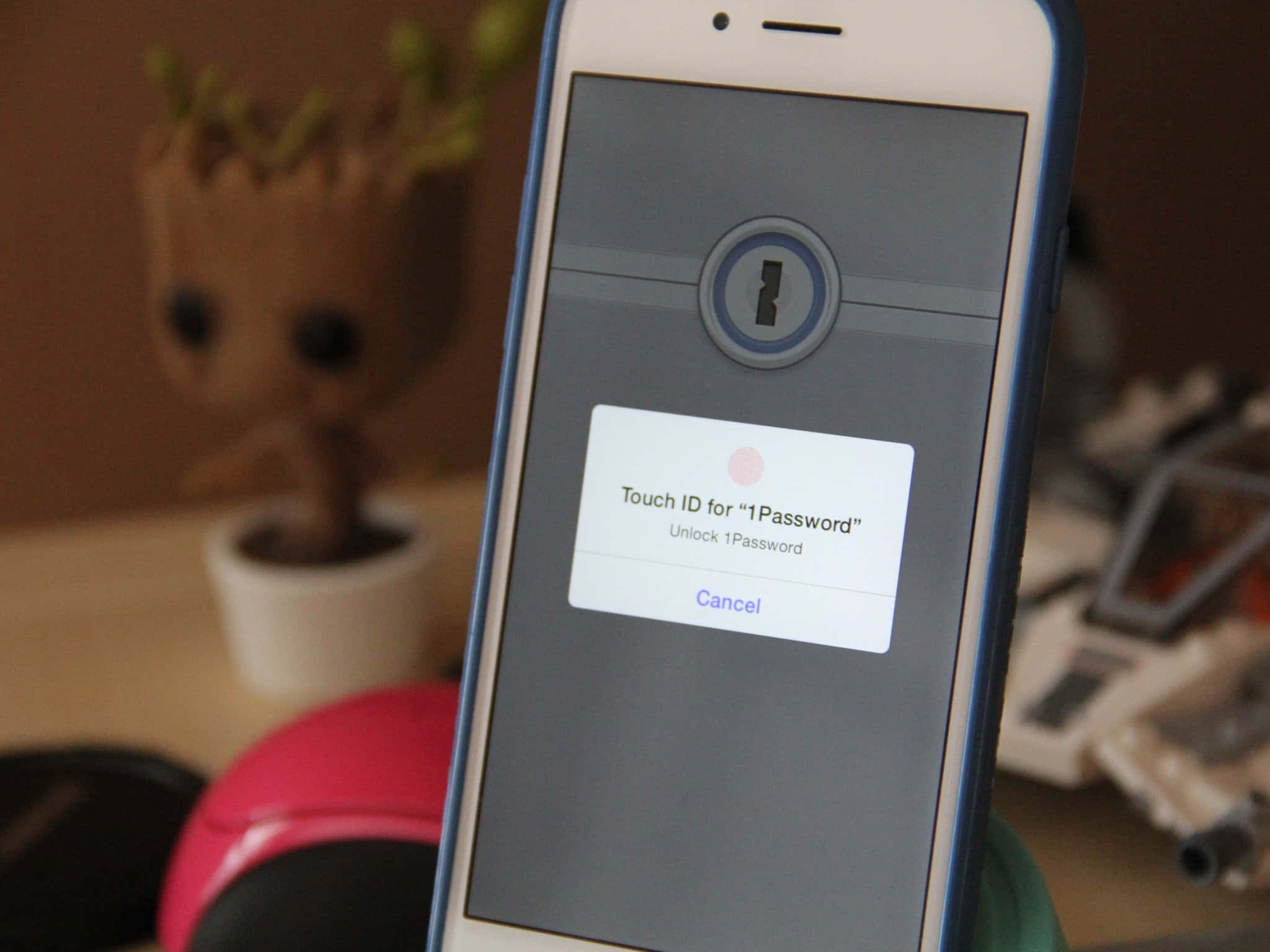 Touch Id 桌布 壁紙 — 一支智慧型手機顯示 Touch ID 提示以解鎖 1Password 應用程式，背景模糊中有 Groot 公仔。