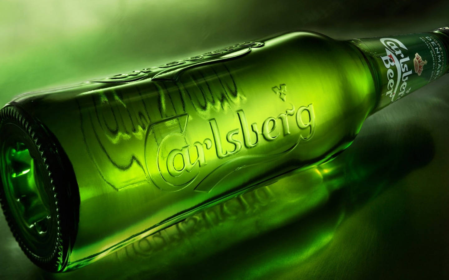 Beer 桌布 壁紙 — 一支有光澤的綠色嘉士伯啤酒瓶以對角線放置在反光表面上，在戲劇性的綠色燈光下。