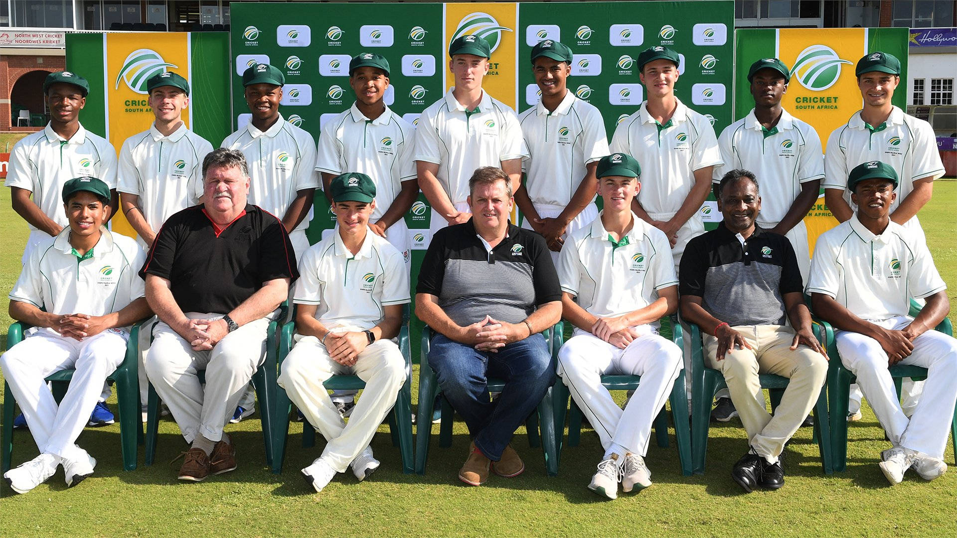 south africa cricket 桌布 壁紙 — 一支板球隊穿著白色制服和綠色帽子，在草地上以品牌背景前正式擺姿勢。