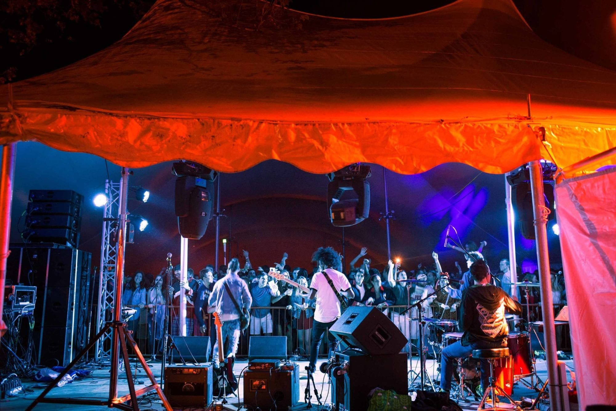 band 桌布 壁紙 — 一支現場樂團在夜間於發光的橙色帳篷下表演，熱情的人群歡呼喝采。