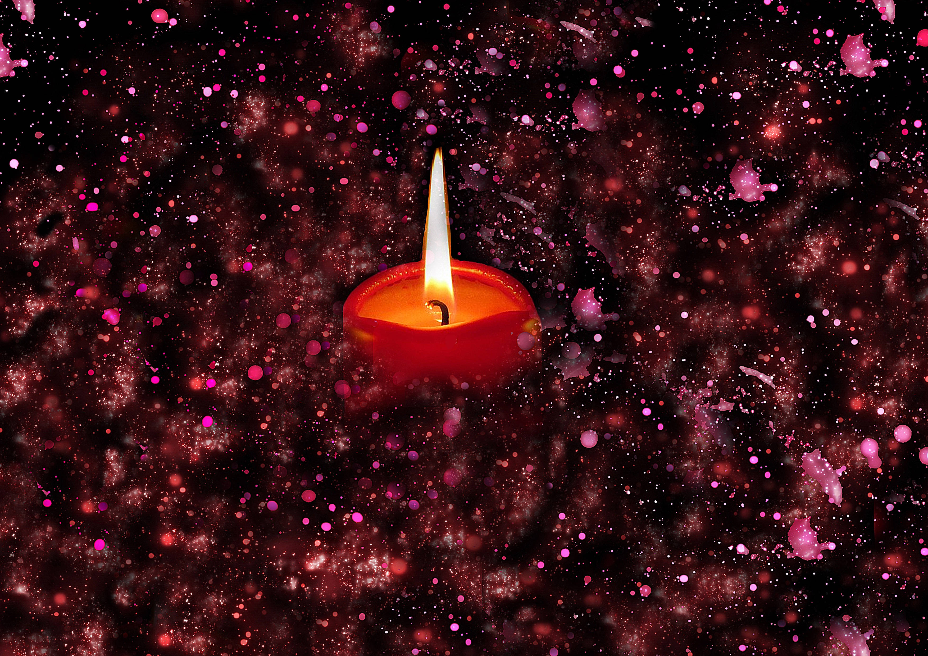 閃爍 桌布 壁紙 — 一支發光的紅色蠟燭在黑暗的宇宙背景下明亮地燃燒，背景點綴著粉紅色和紅色的閃粉粒子。
