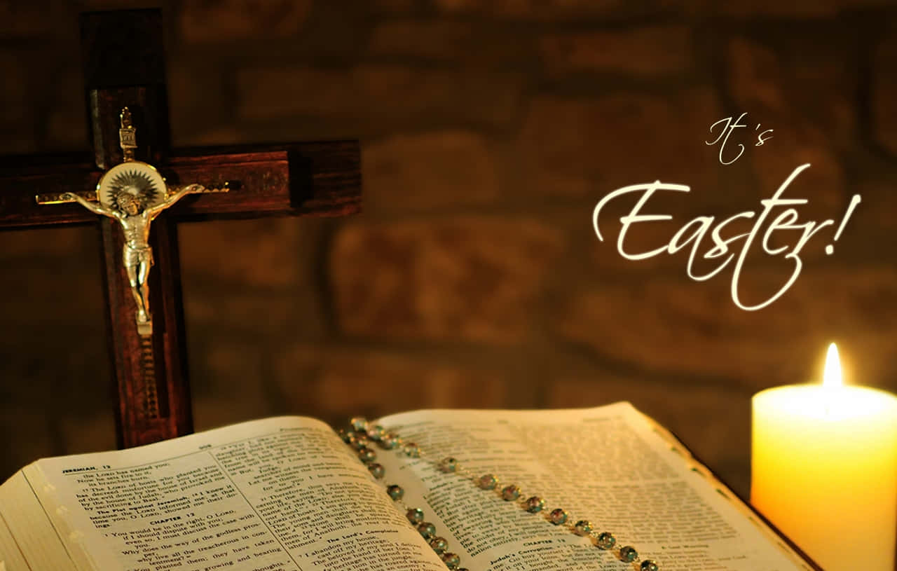 Religious Easter 桌布 壁紙 — 一支發光的蠟燭照亮了一本打開的聖經和一個十字架，背景是磚牆，上面用光寫著「這是復活節！」。