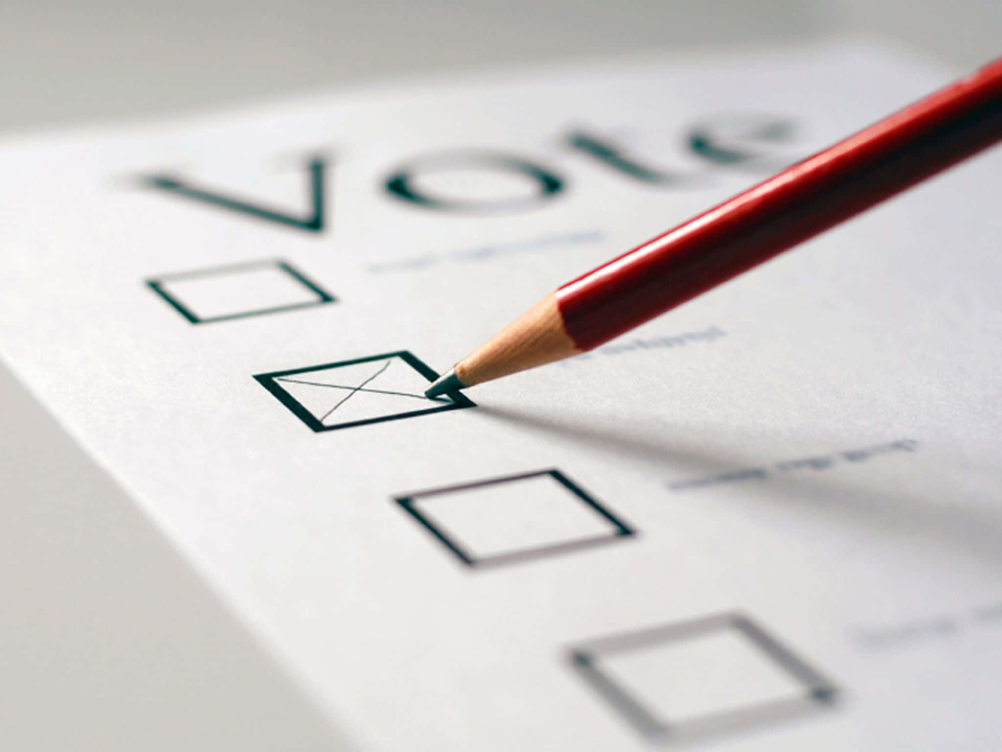 選舉 桌布 壁紙 — 一支紅色鉛筆在投票選票上標記一個核取方塊，Vote 字樣在柔和焦點中可見。