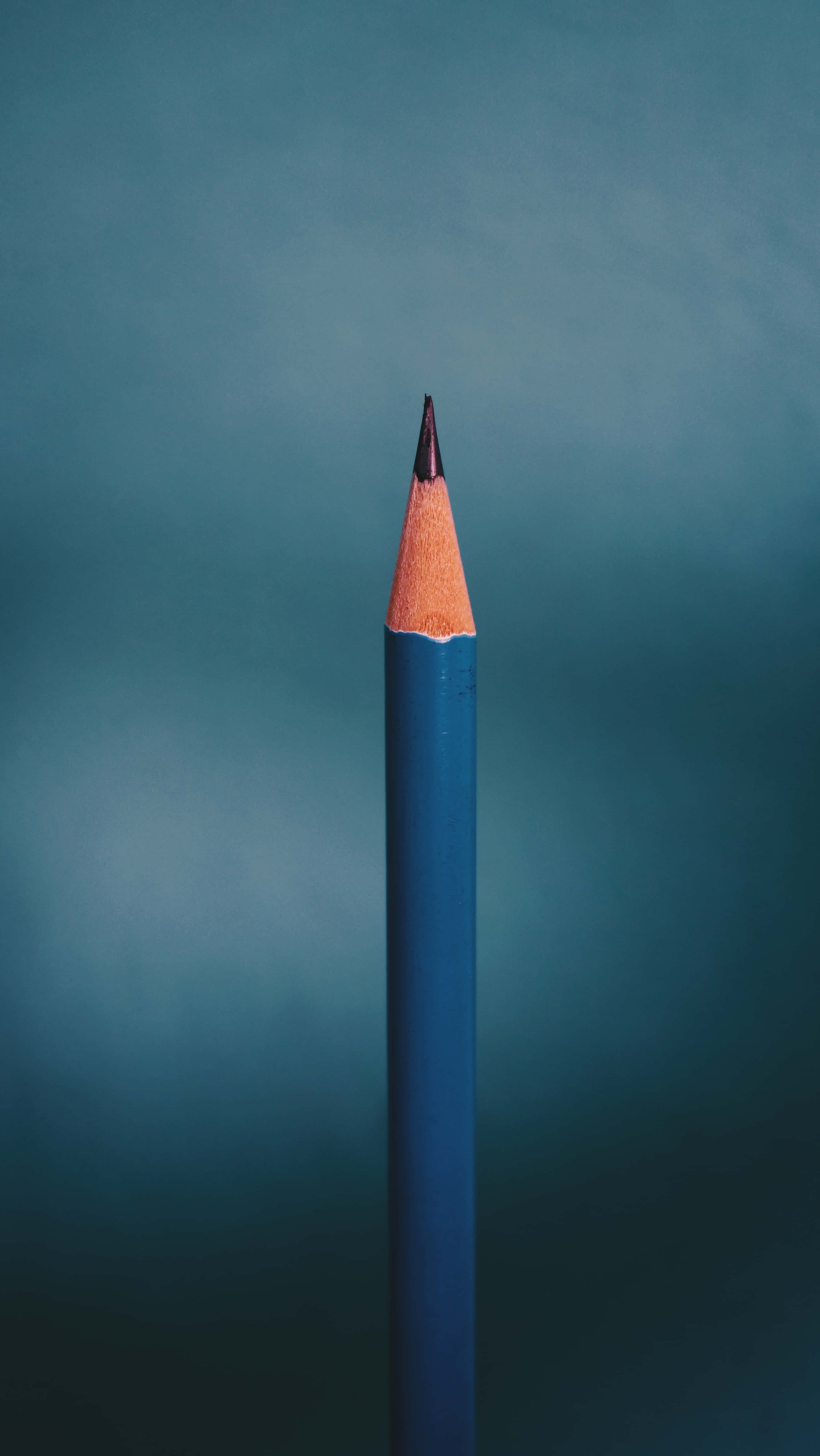 pencil 桌布 壁紙 — 一支藍色鉛筆筆尖鋒利，帶橙色木質筆尖，垂直立在柔和的青綠色漸變背景上。
