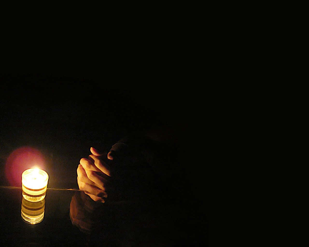 Praying Hands 桌布 壁紙 — 一支蠟燭在深沉的陰影中將溫暖的光芒投射在緊握的雙手上，喚起靜默的沉思。