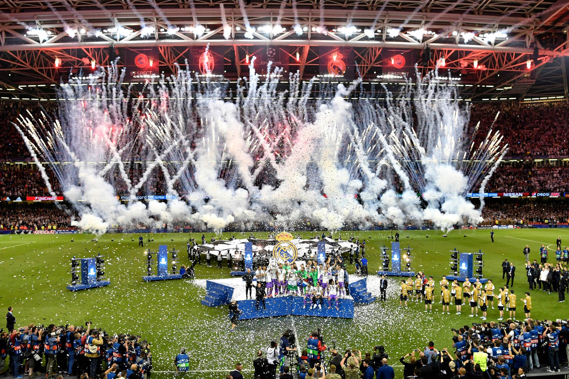 Champions League 桌布 壁紙 — 一支足球隊在球場上慶祝勝利，煙火在他們頭頂爆炸，五彩紙屑如雨般落下。