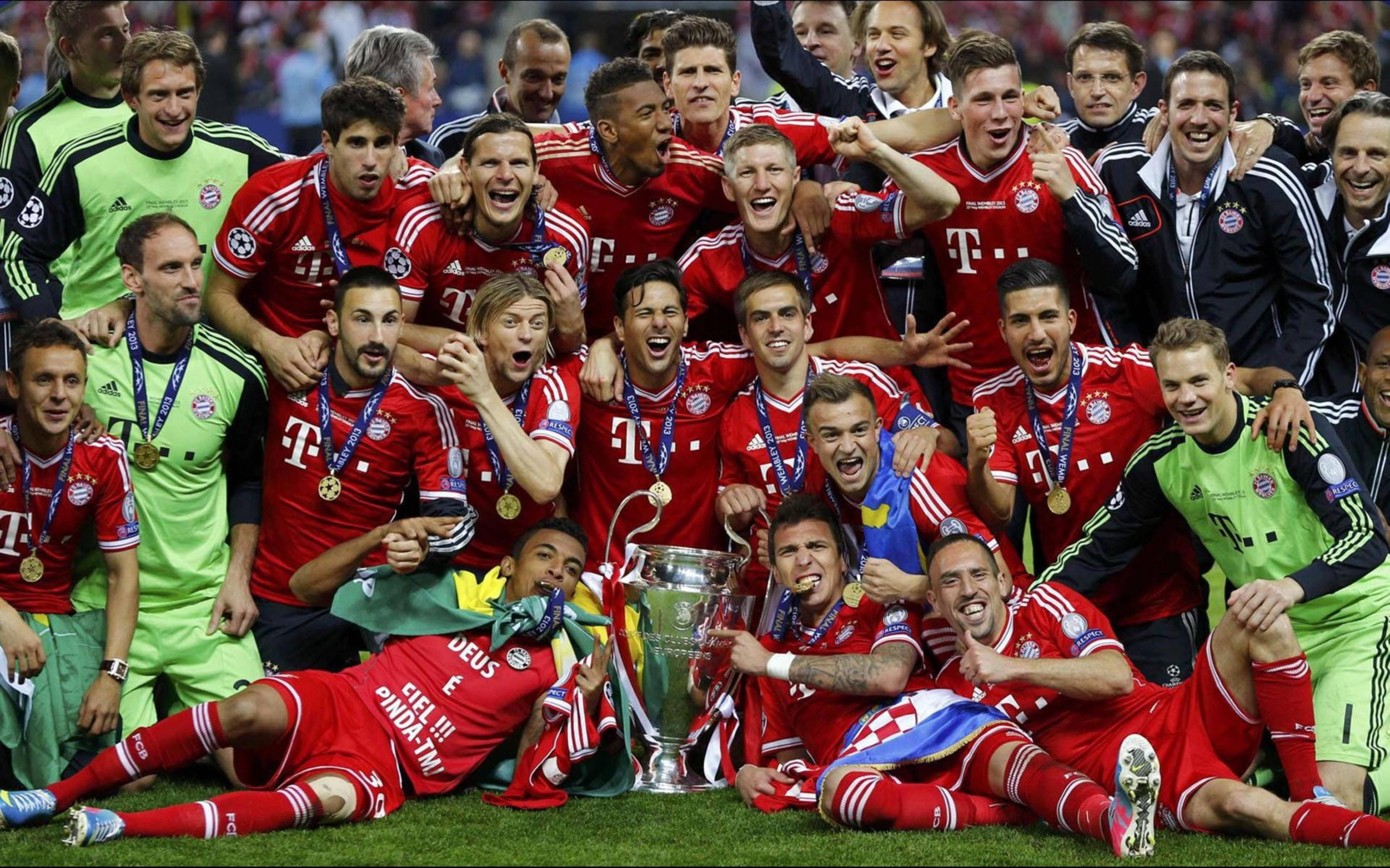 Bayern 桌布 壁紙 — 一支身穿紅色球衣的歡騰足球隊在體育場草坪上慶祝，手持獎盃和金牌。