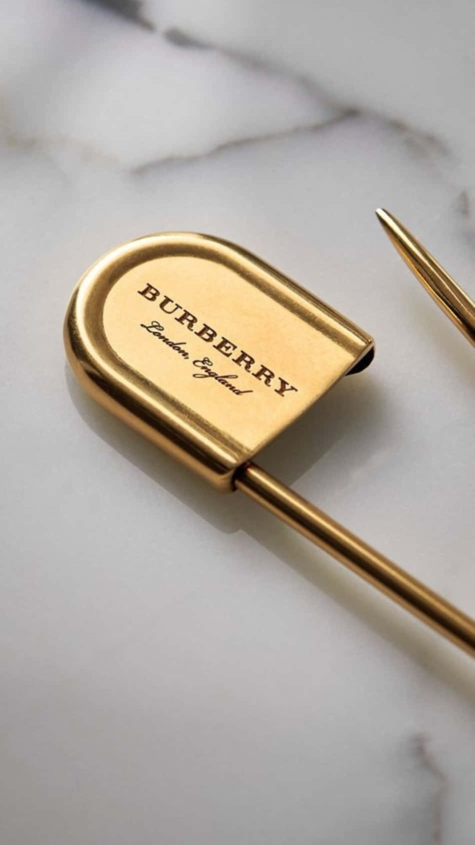 Burberry 桌布 壁紙 — 一支金色 Burberry 品牌鋼筆優雅地放在帶有灰色紋理的白色大理石表面上。