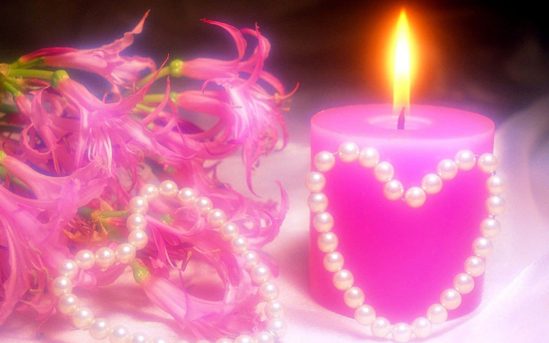 love you 桌布 壁紙 — 一支閃爍的粉紅色蠟燭，飾有珍珠心形，旁邊擺放著精緻的粉紅色花朵和散落的珍珠，置於柔軟的表面上。