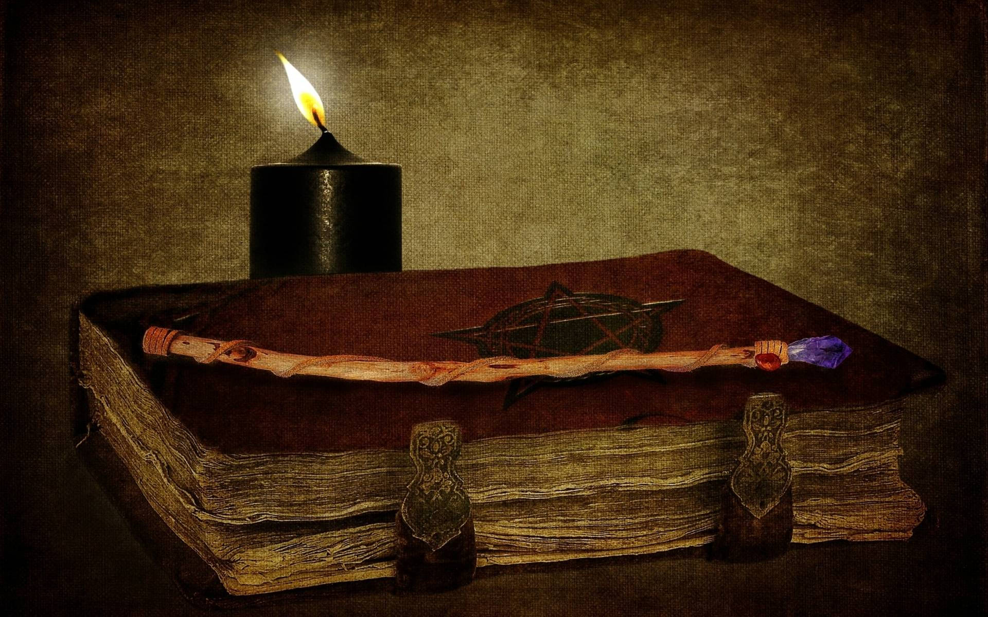 witchcraft 桌布 壁紙 — 一支閃爍的黑蠟燭照亮了一本古老的書，書上有一個五角星和一根沾滿血跡的魔杖，擱在破舊的皮革封面上。