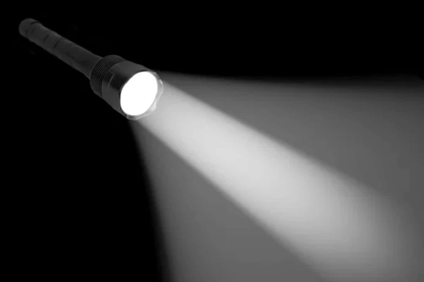 Flashlight 桌布 壁紙 — 一支黑色手電筒在黑暗虛空中射出明亮的白光，形成強烈對比和方向感。